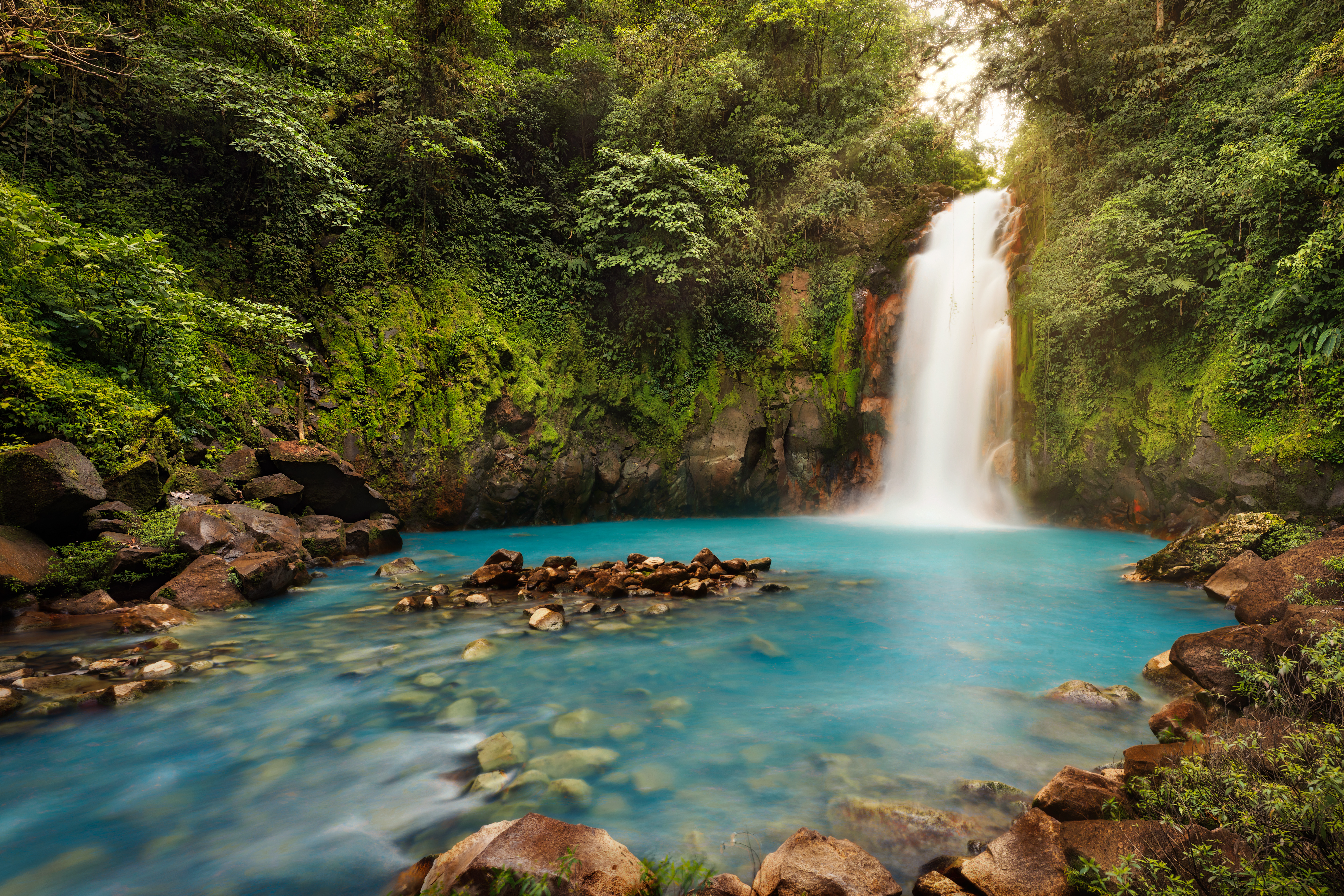 The powerful Rio Celest Waterfall plunges 100 feet into a pool of bright blue water surrounded by dense tropical forest