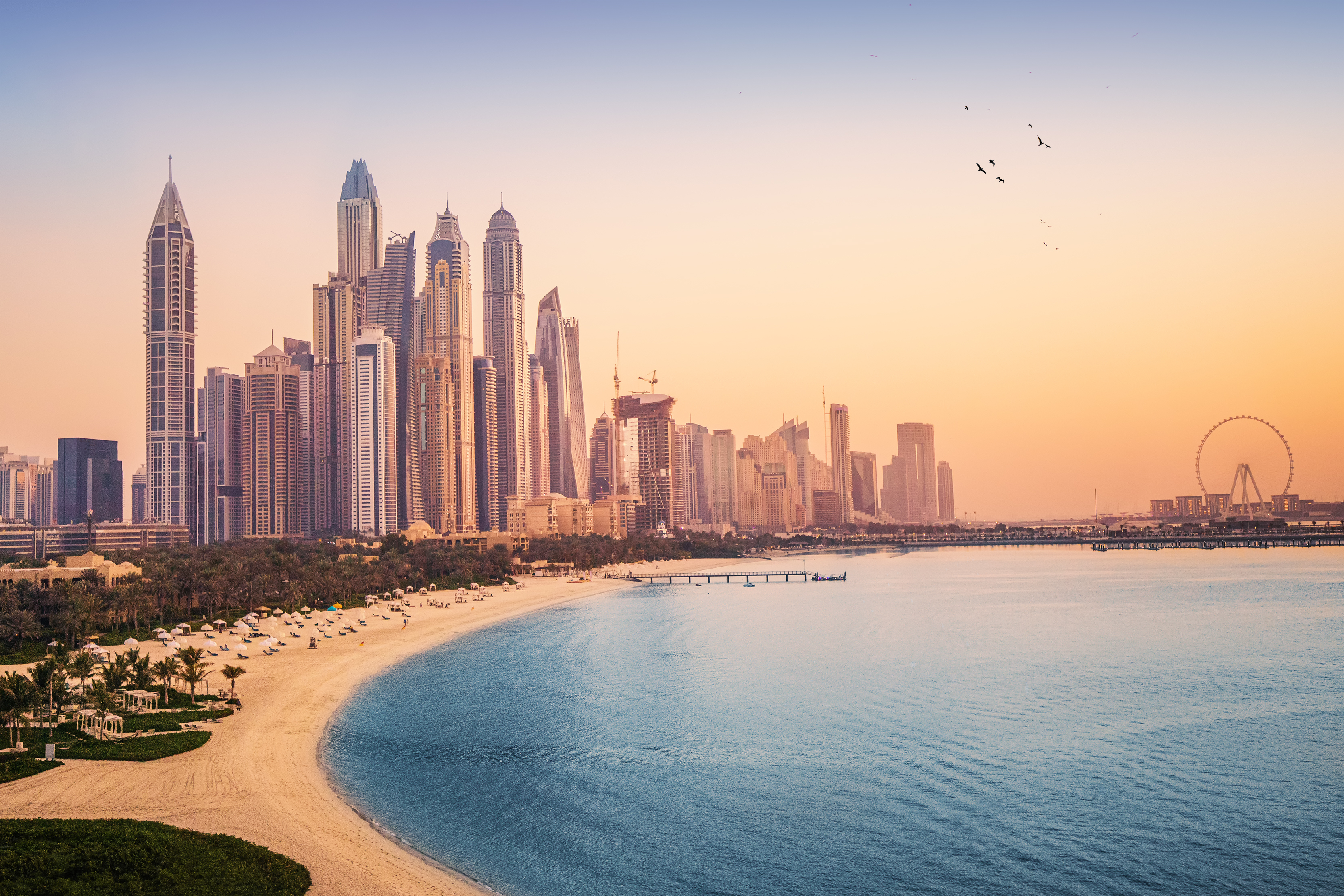 Sunset view of the Dubai Marina and JBR area and the famous Ferris Wheel and golden sand beaches in the Persian Gulf.