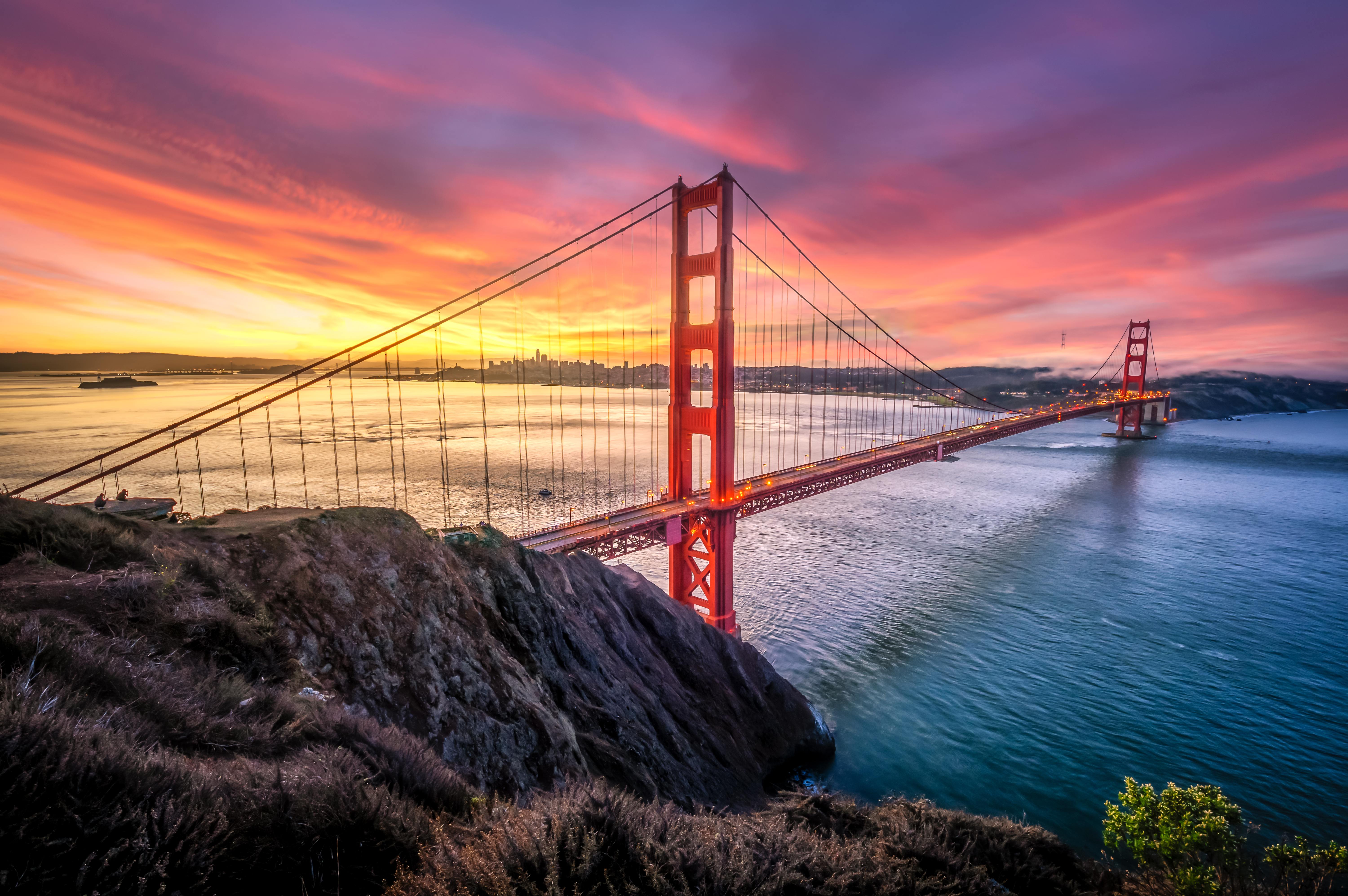 Colored sunrise with wide shot of bridge and city in the background