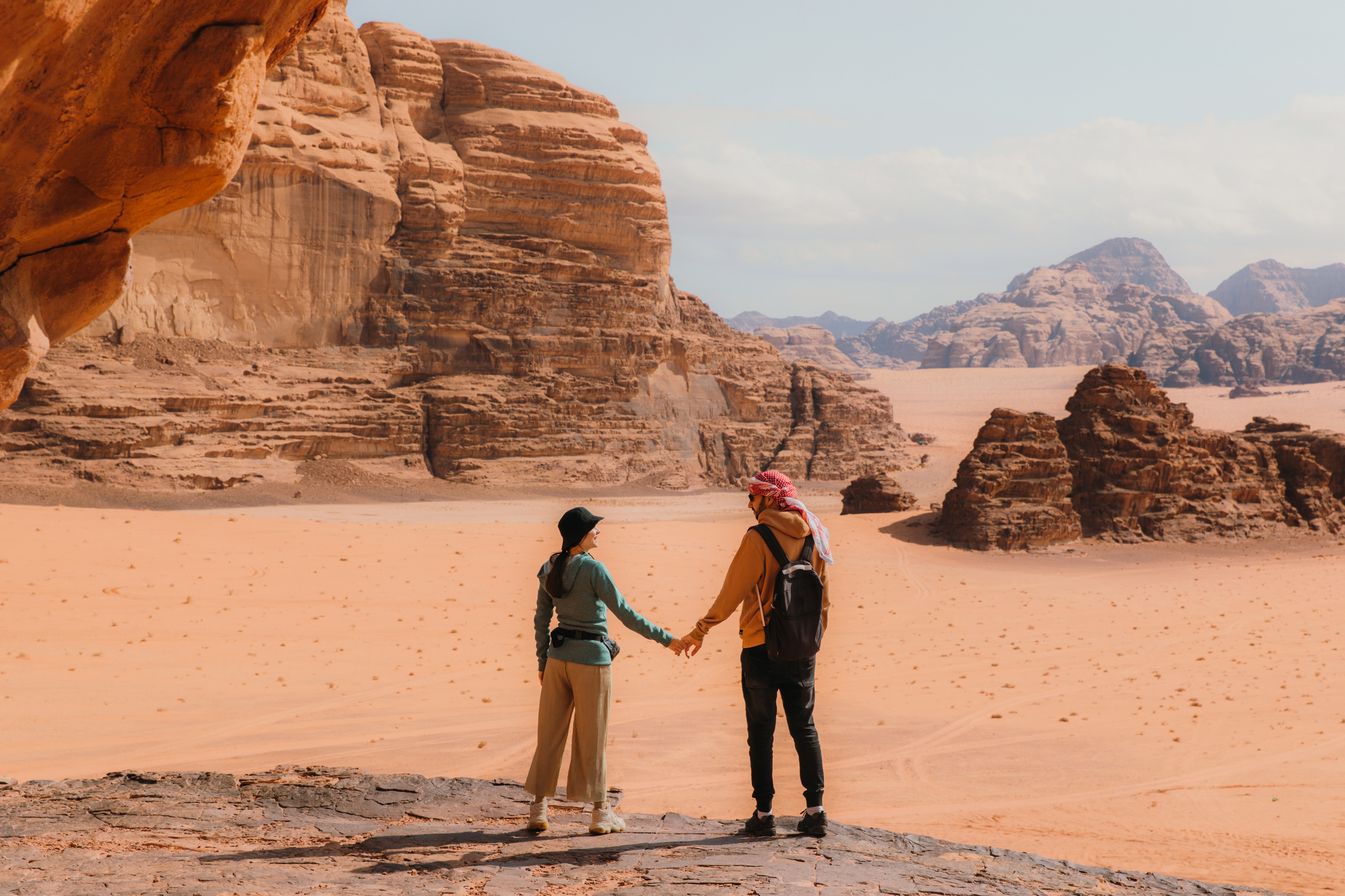 Young woman and man traveler contemplating the scenic landscape of Wadi Rum desert