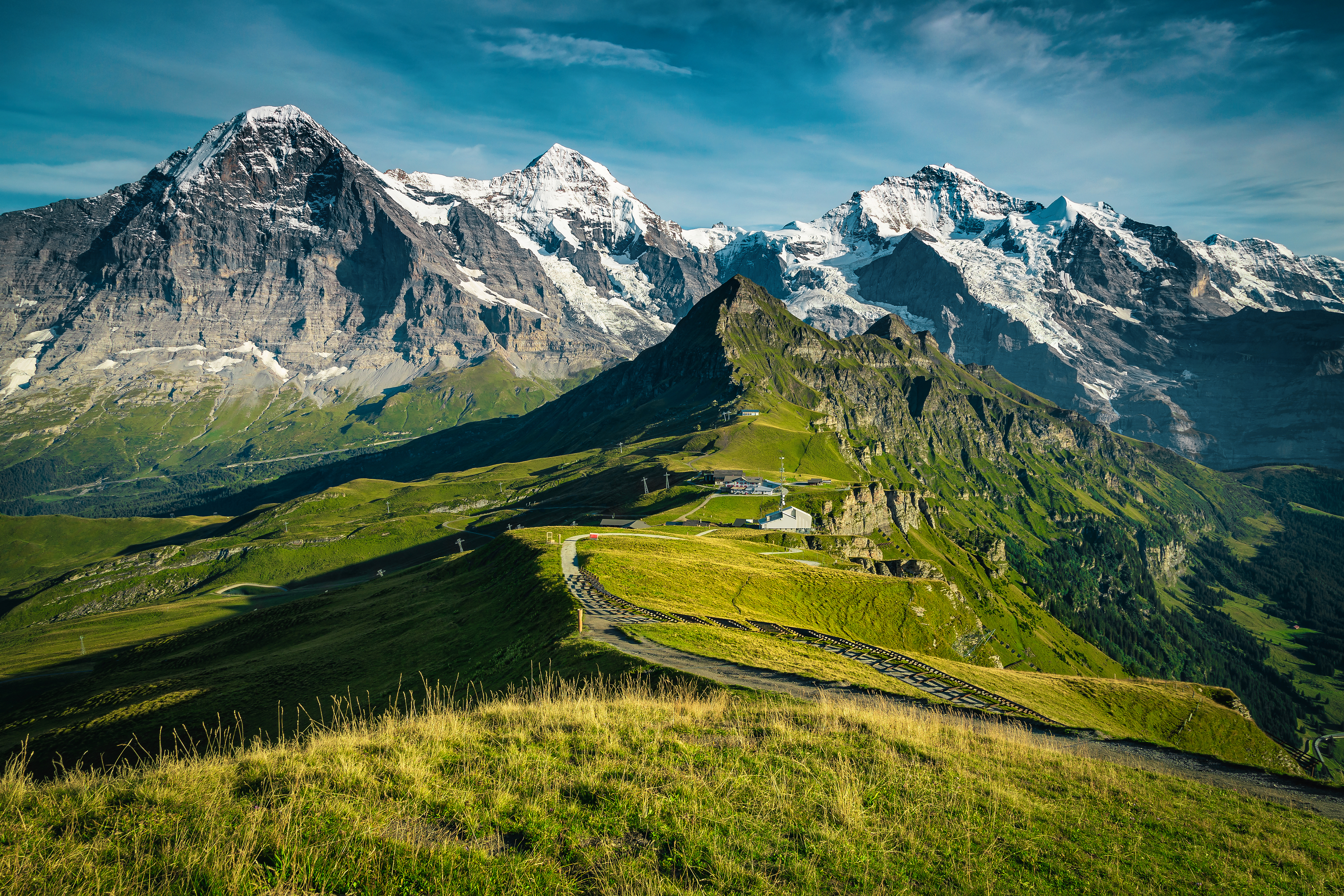 Picturesque snowy mountain ridges and deep valleys with green fields.