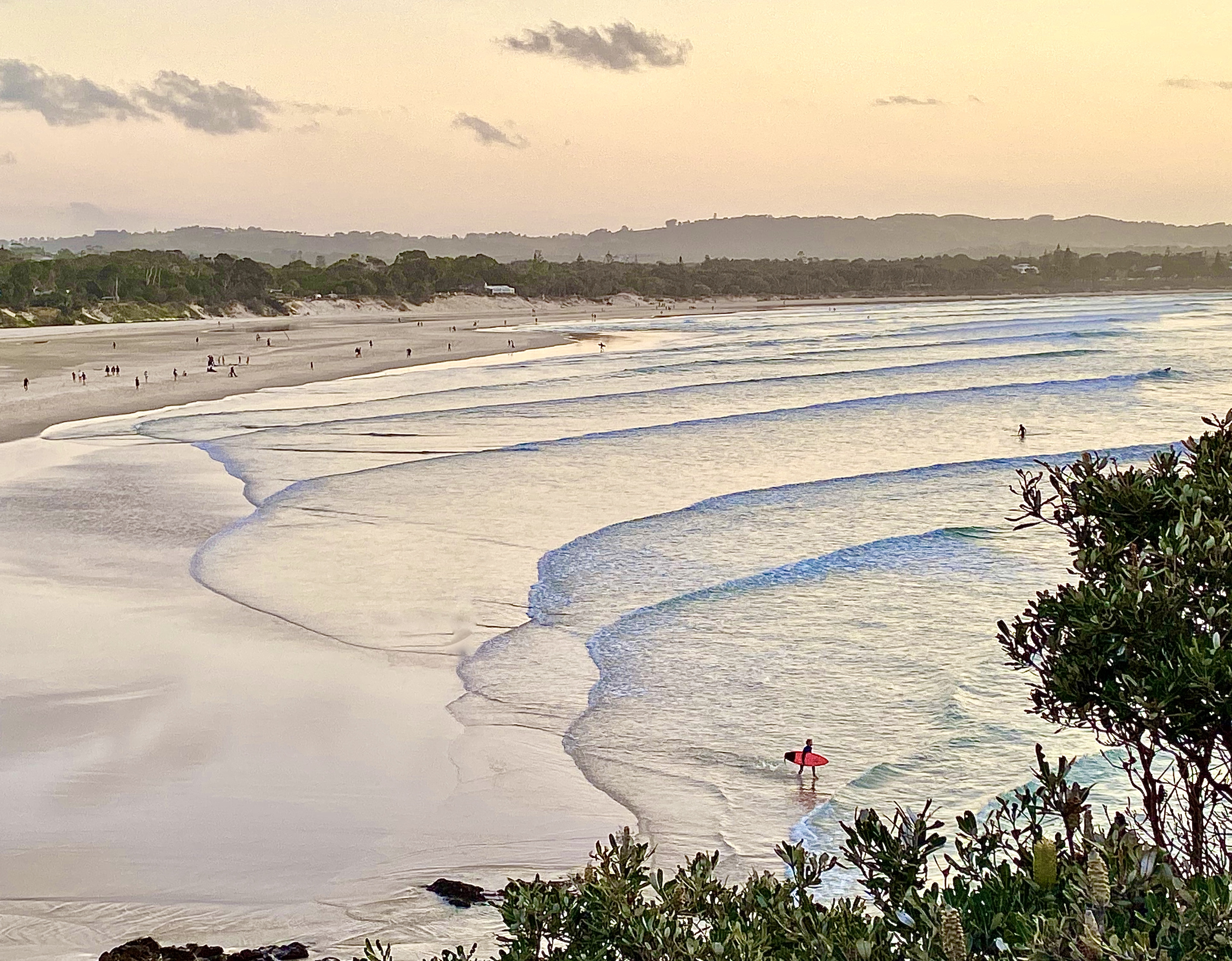 View of sunset seascape and shoreline after surfing calm breaking waves under a pastel color sky at Byron Bay NSW Australia