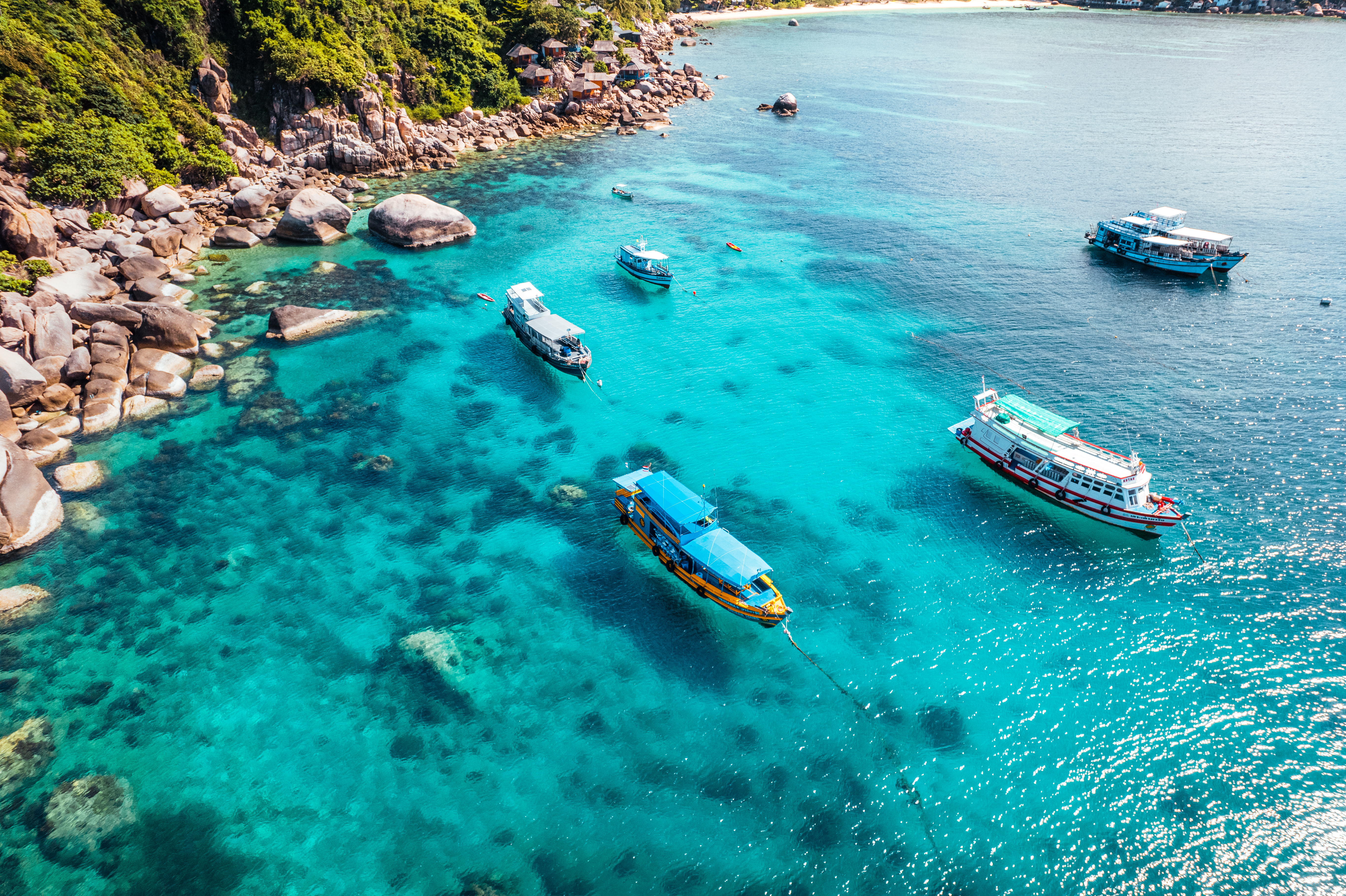 Boats and crystal clear waters at the bay dive site from above