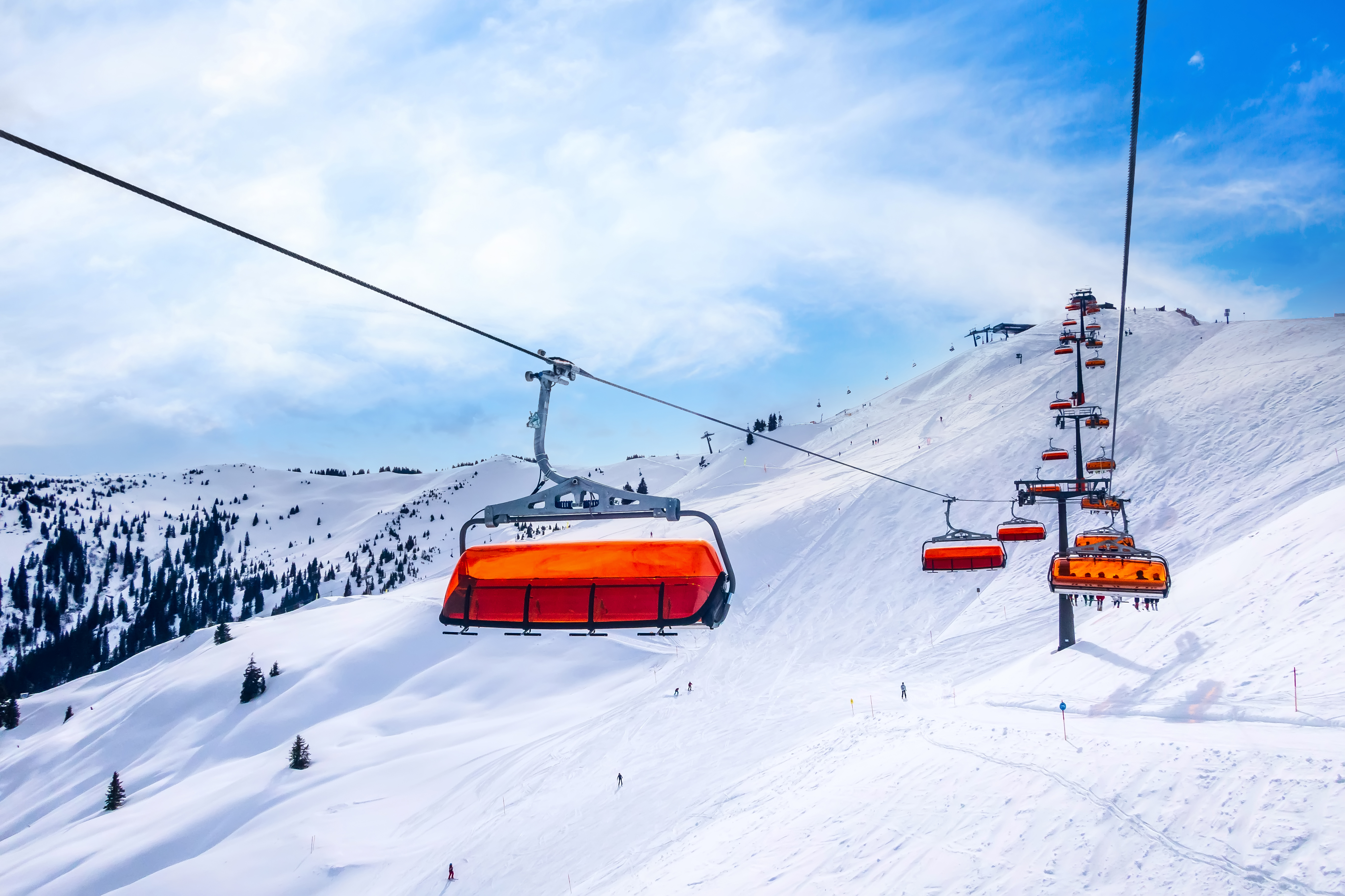 Chair ski lift with orange bubble shelter and ski slope in Saalbach Hinterglemm resort