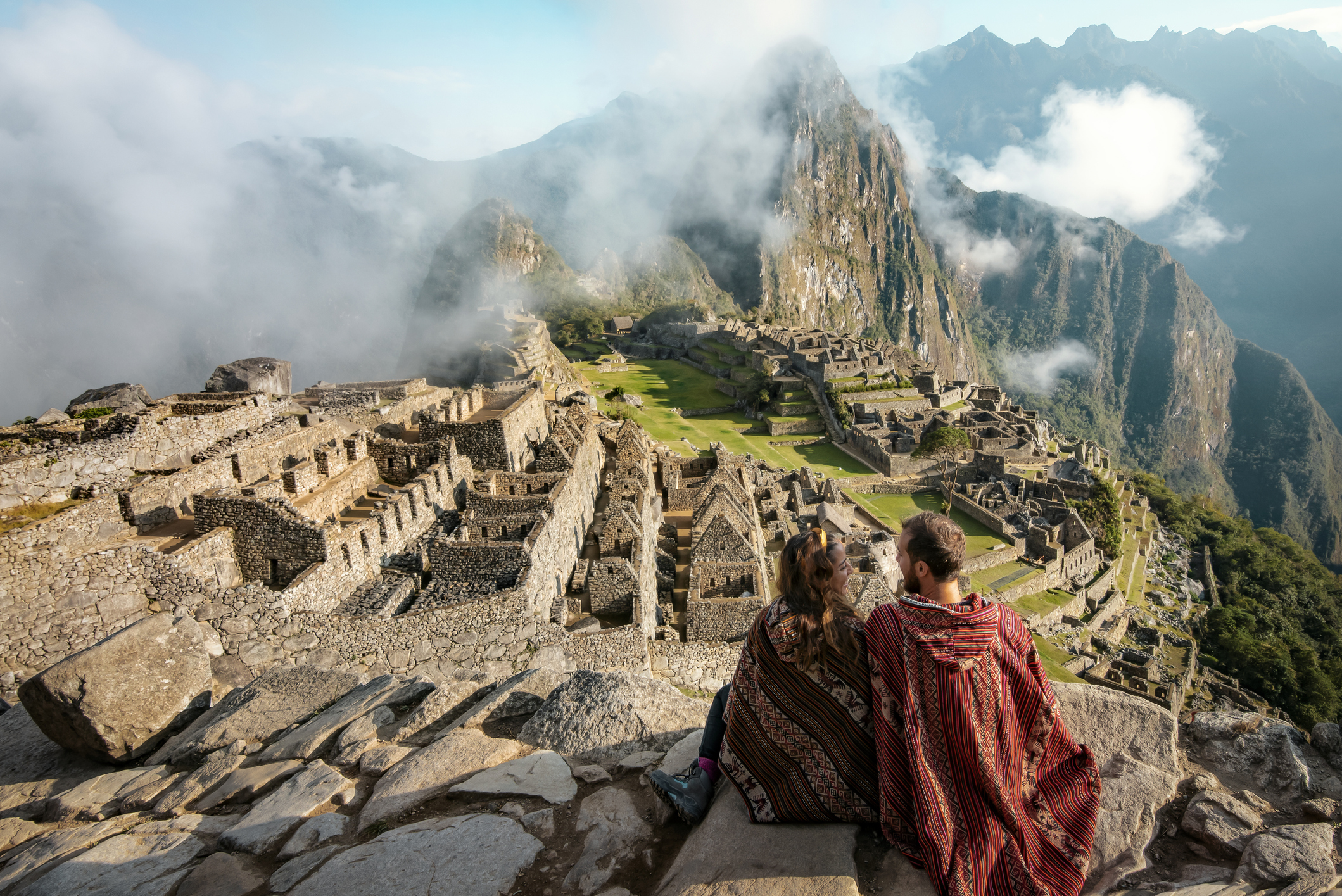 A couple sits atop the ancient Machu Picchu