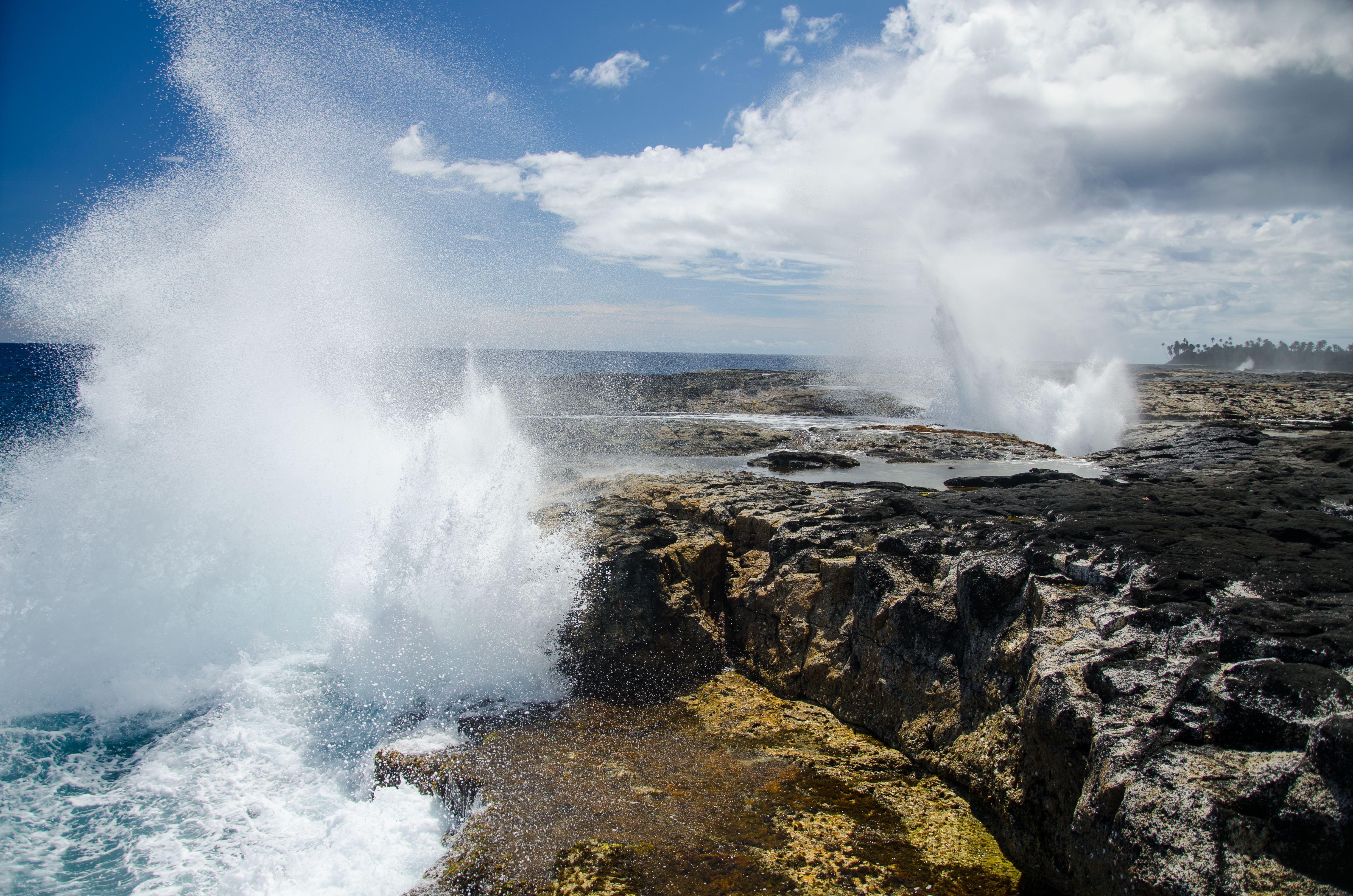 The Alofaaga Blowholes send water towards the bright blue sky along the ocean in Somoa