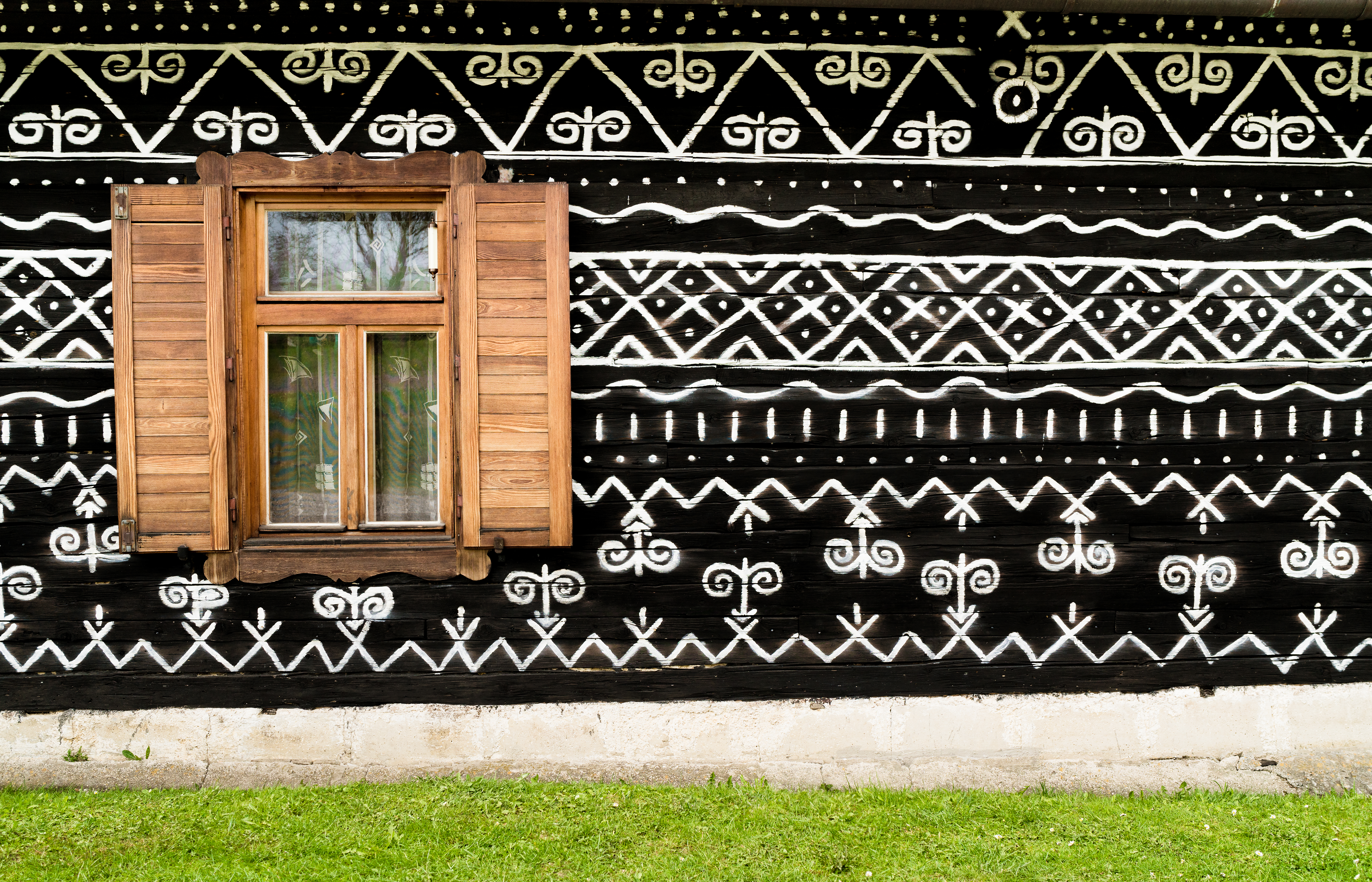 Wooden window on the White and black pattern ornament painting on the dark wood wall in Slovakian old village Cicmany