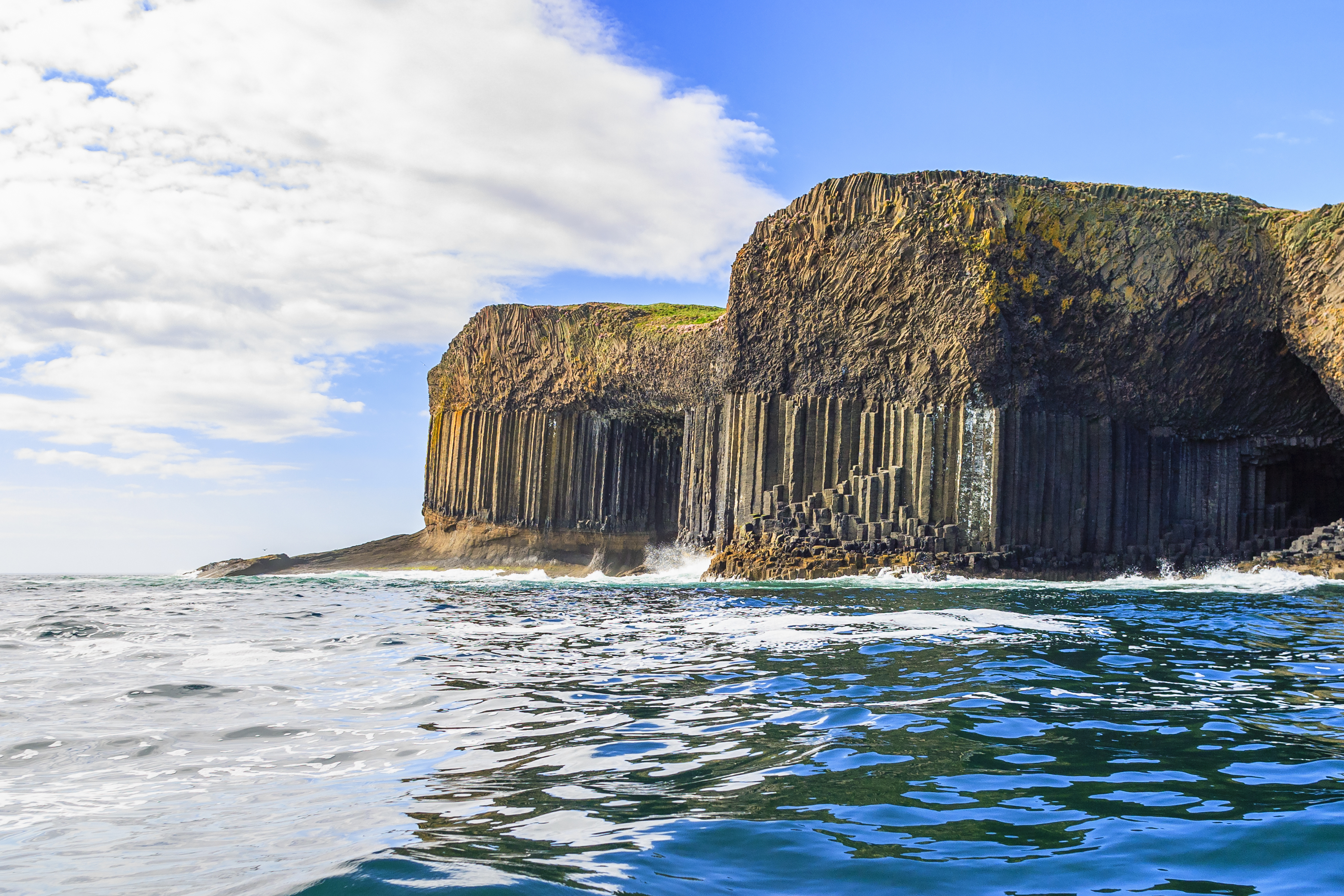 Magnificent rock formations and caves rising from the ocean against cliffside