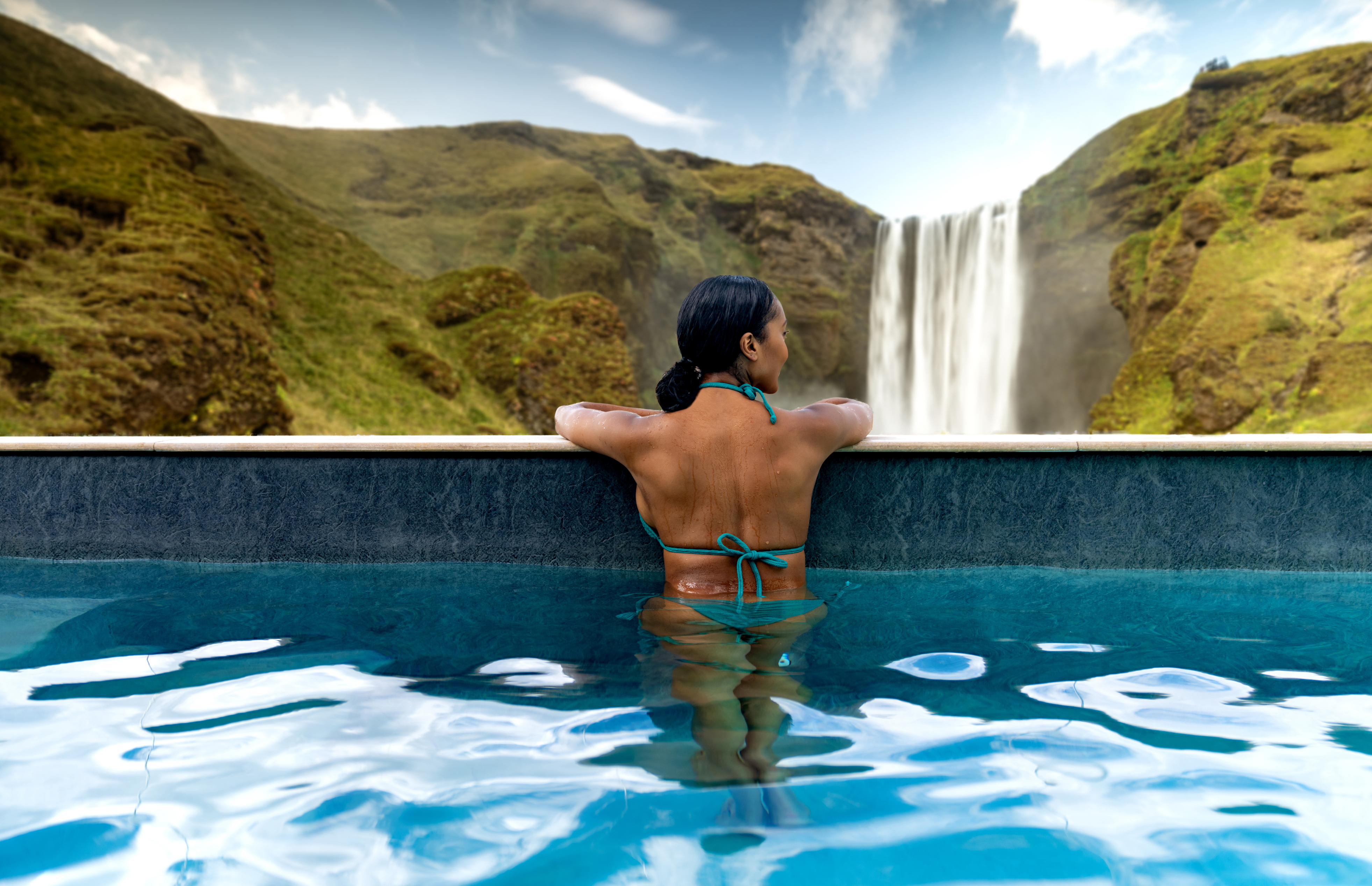 A woman relaxes in a pool while watching a waterfall 