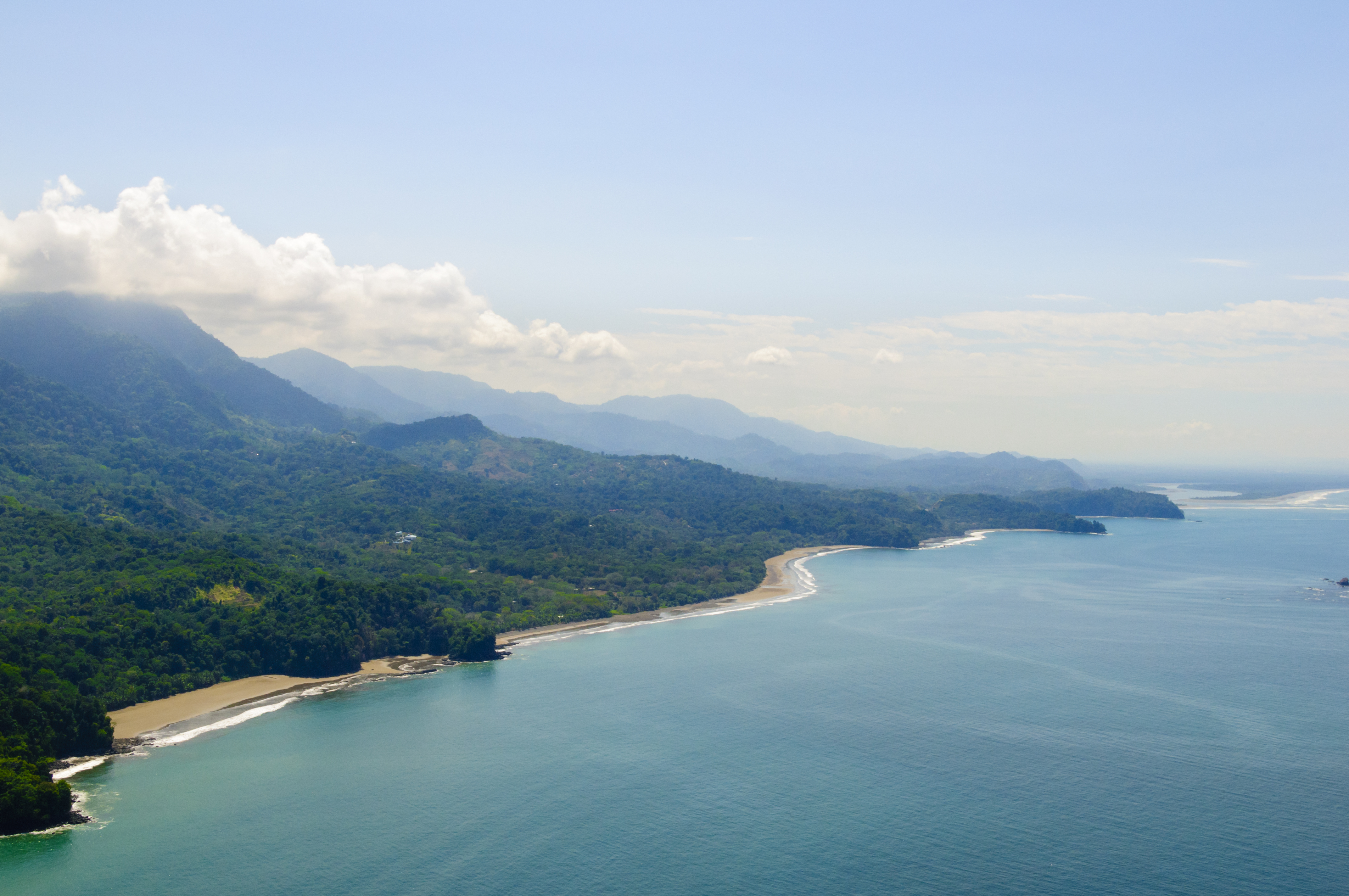 Vibrant tropical forests flow down from the mountains to the sandy beaches along the coast. Aerial view of the Costa Ballena near Dominical, Costa Rica