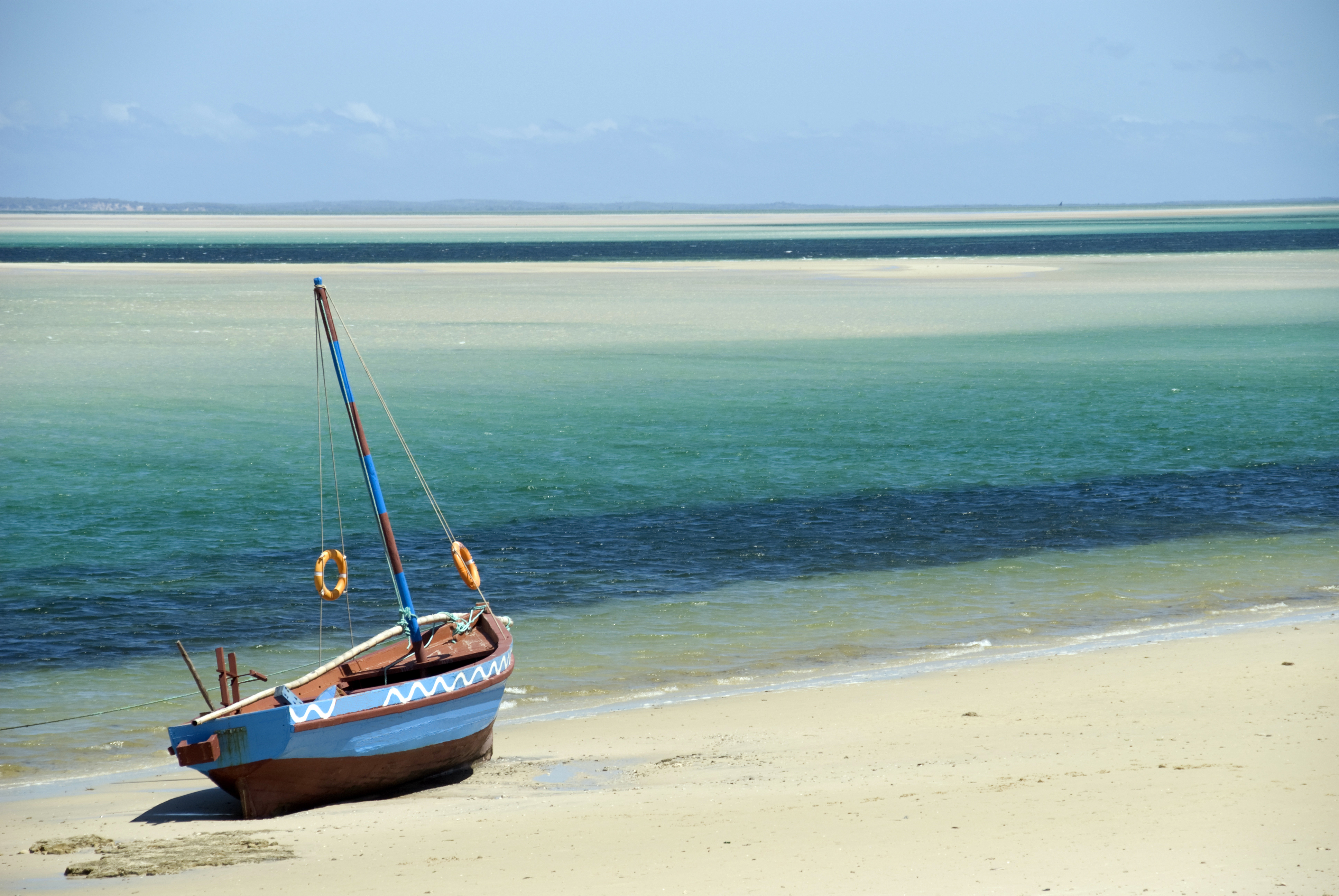 A Dhow (boat) sitting at the water's edge on a beach
