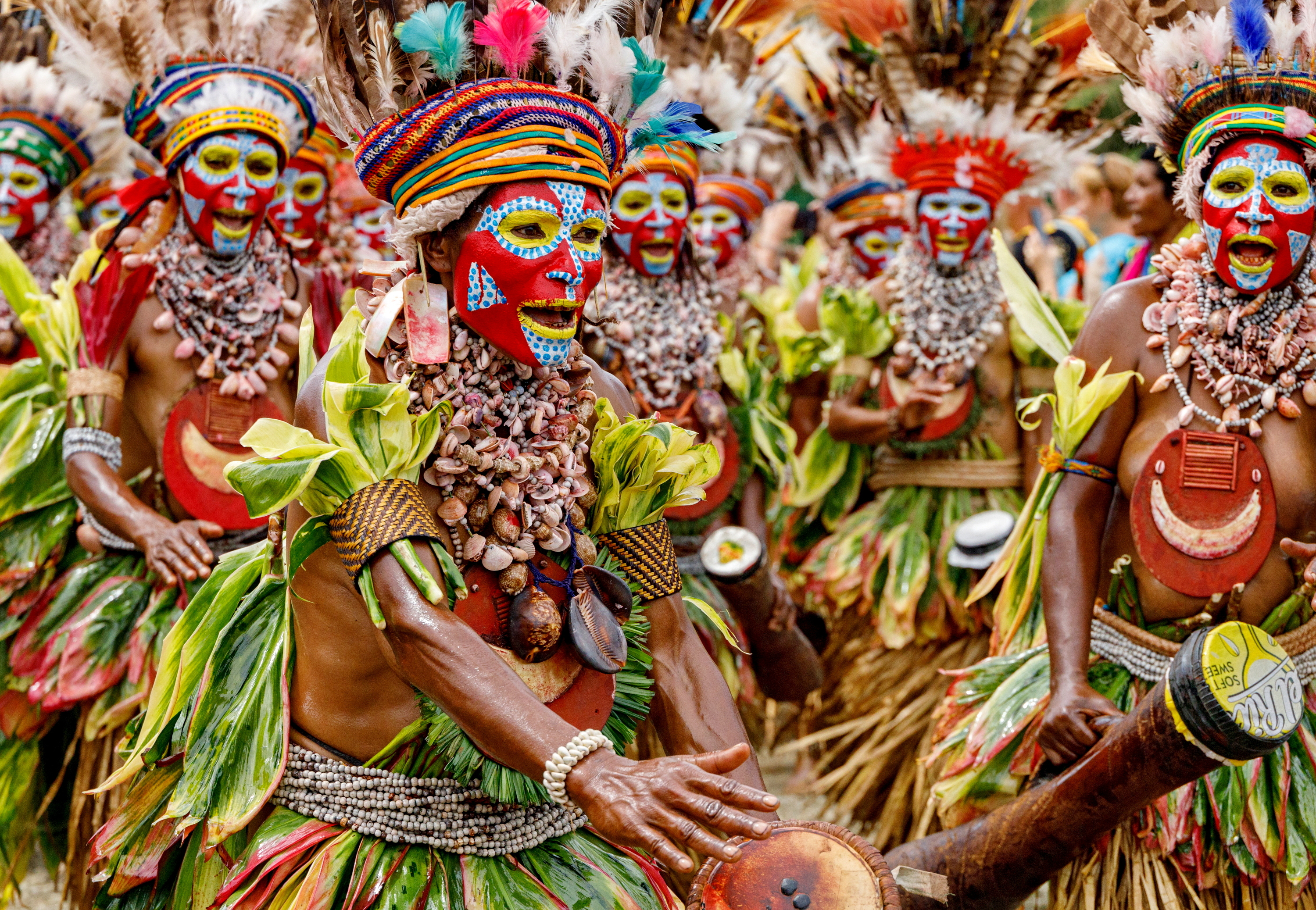 Indigenous dancers in vibrant costumes and face paint perform during a cultural celebration, surrounded by colorful decor.