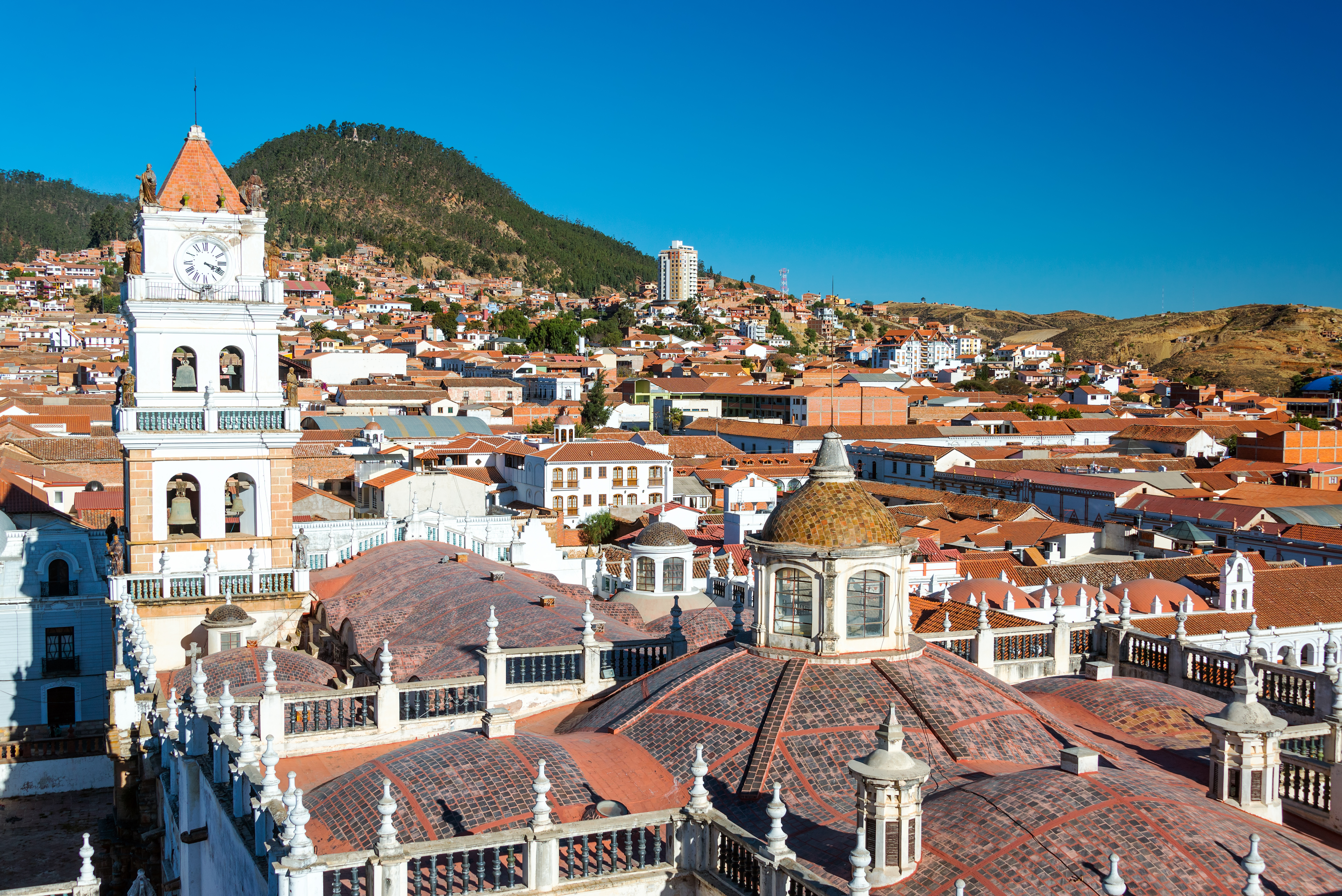 View of white colonial cathedral clocktower and red roofs in Sucre, Bolivia known as the White City