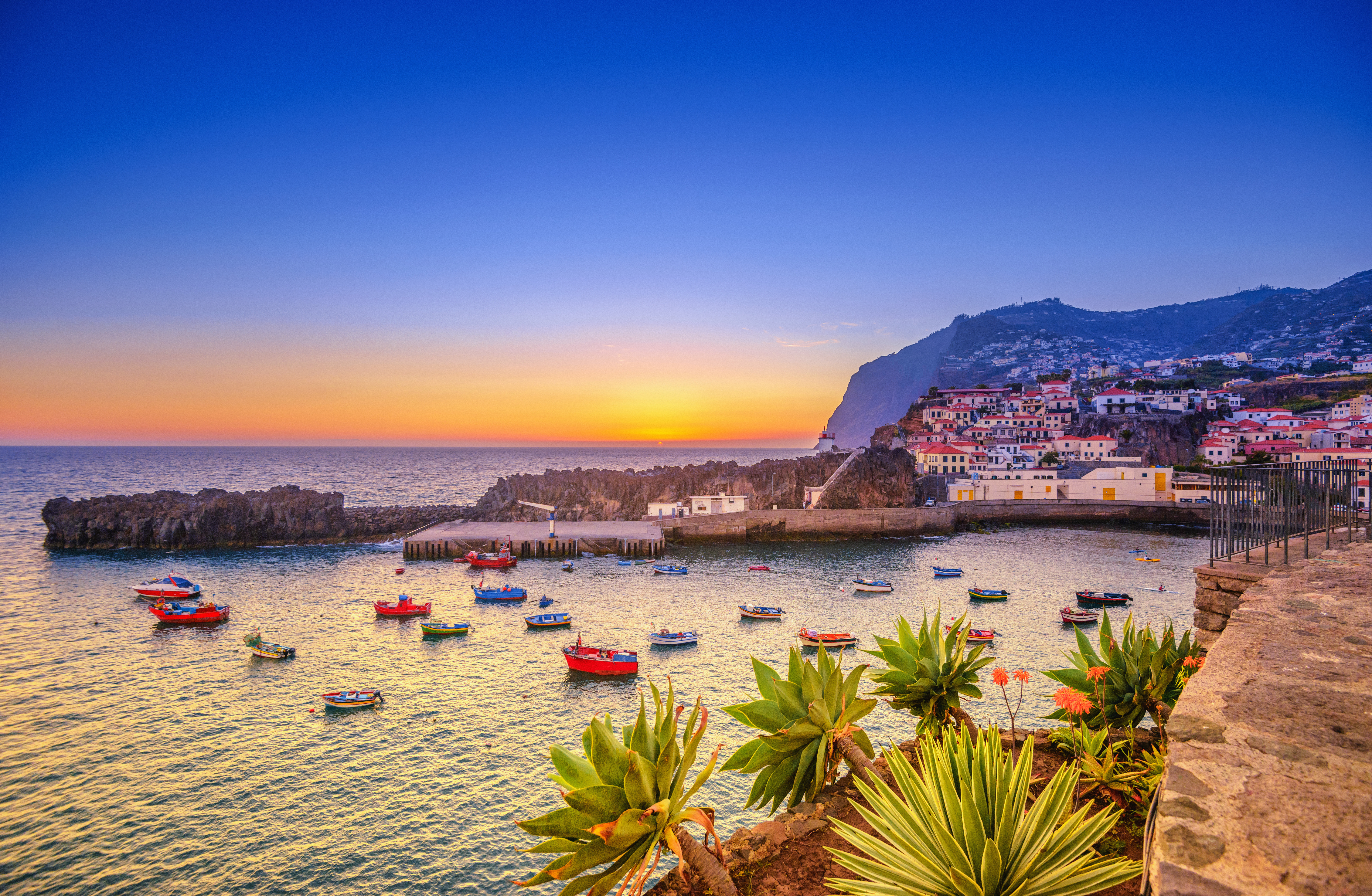The beautiful fishing village, boats in the water and steep cliff in the background