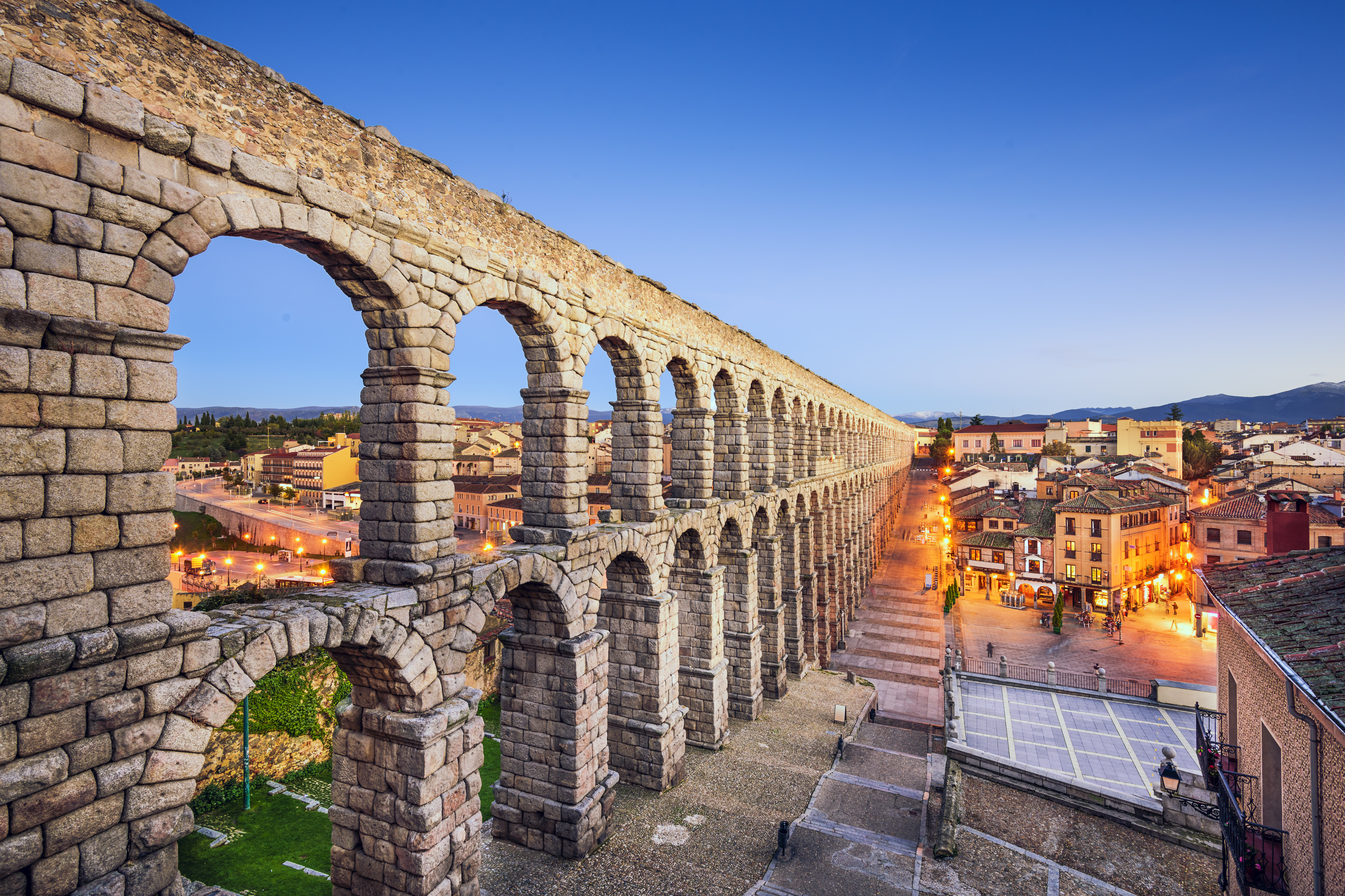 Ancient Roman aqueduct cutting through ancient village at twilight.