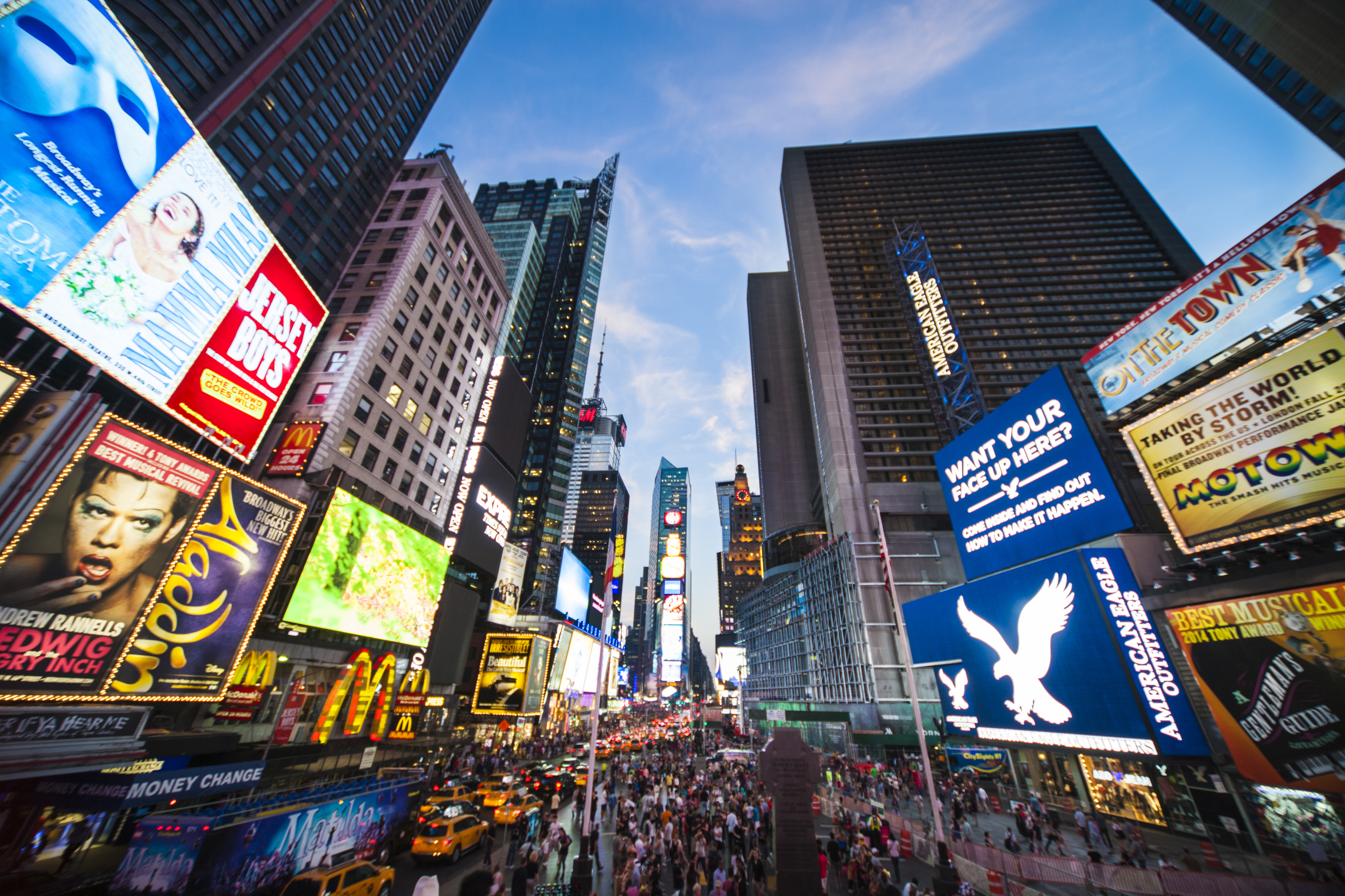 Tourists crossing Times Square surrounded by bright lights and advertisements