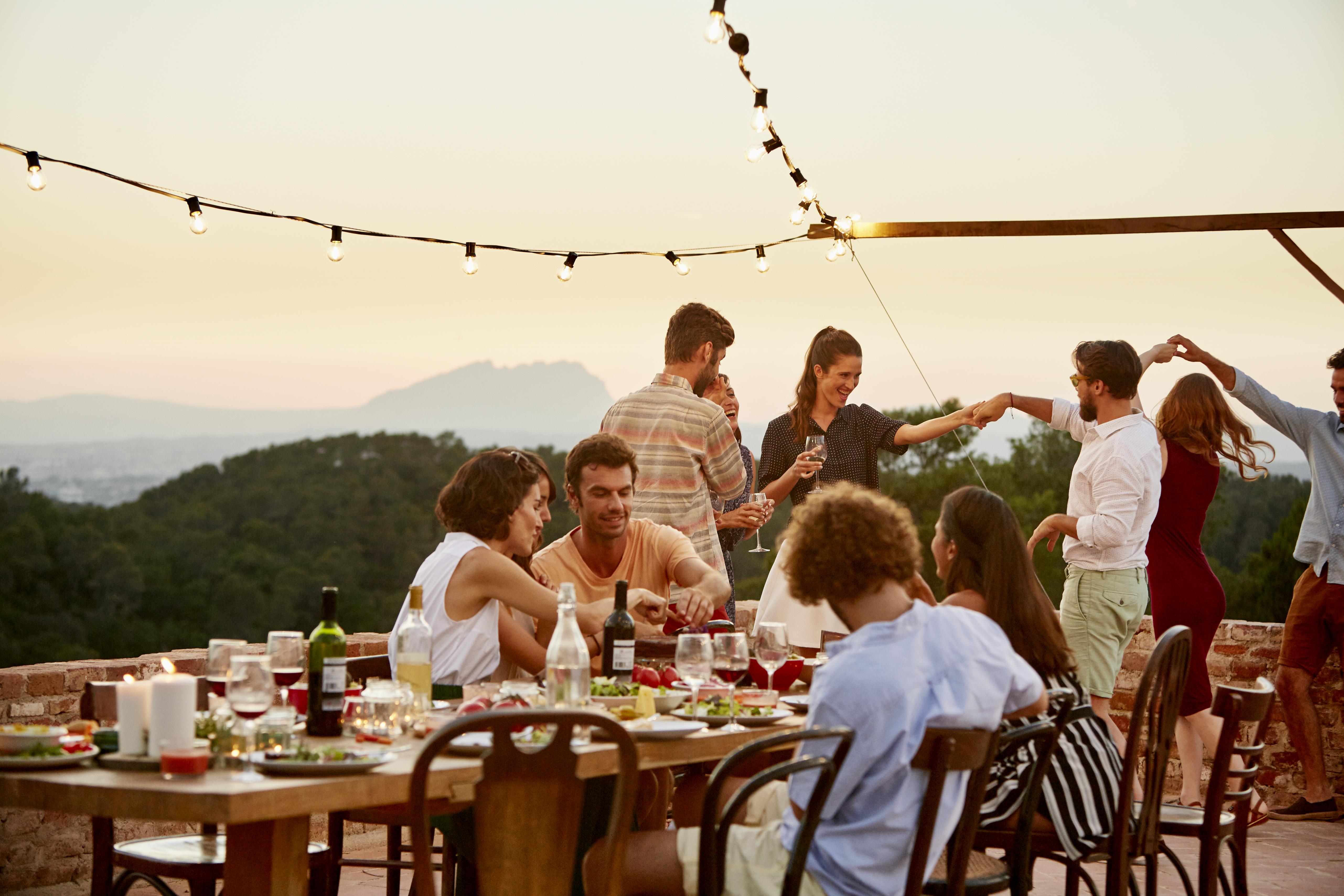 Friends enjoying at patio during social gathering at sunset in Spain