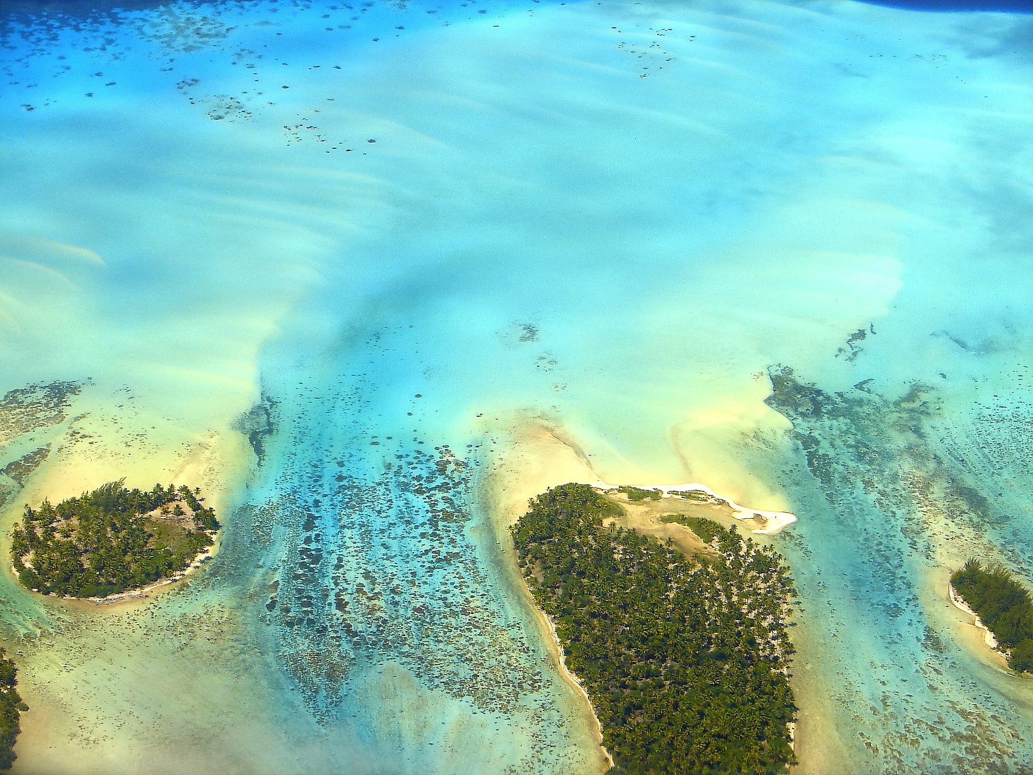 Sandy turquoise tropical beach, motus and reefs aerial view