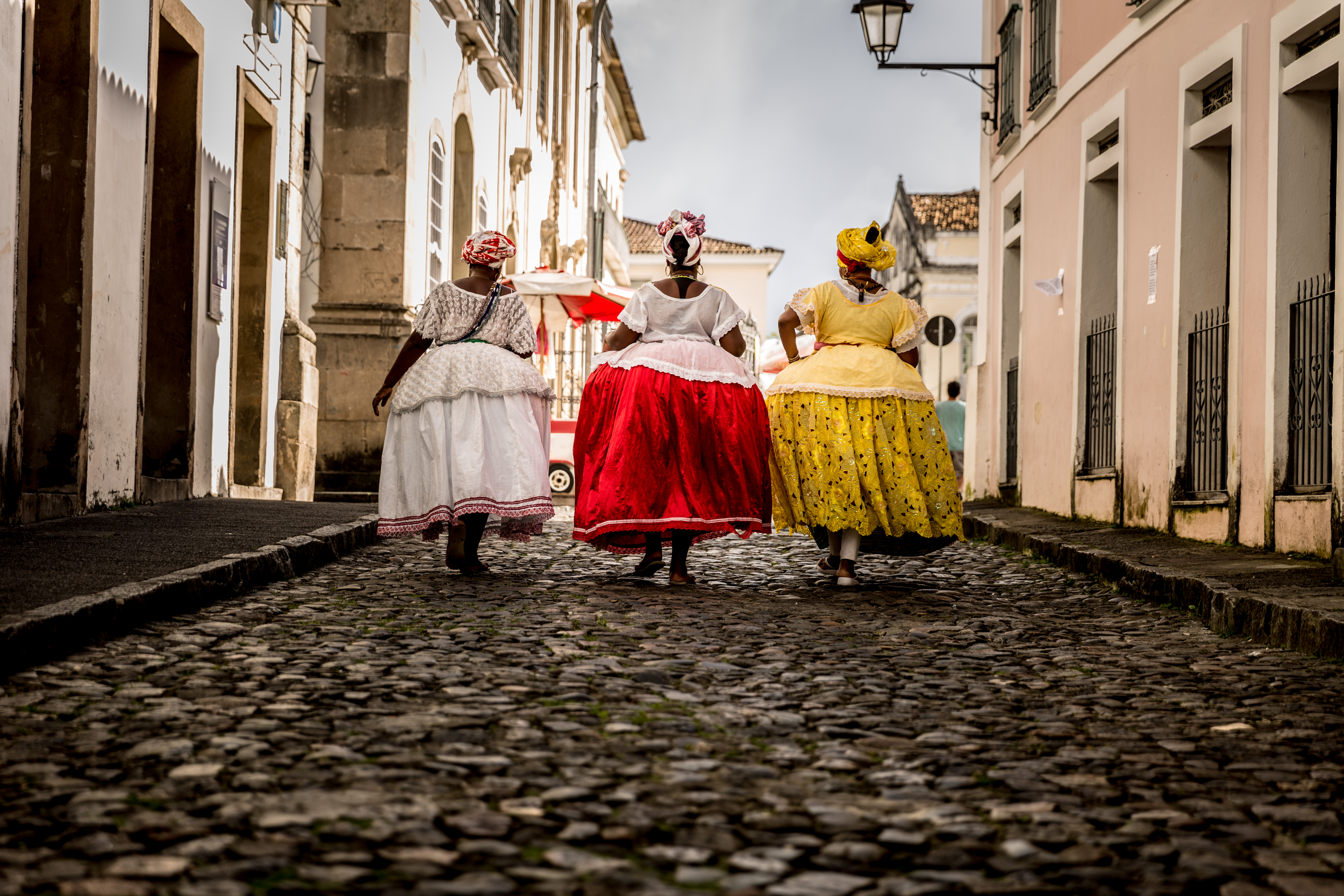 Group of "Baianas" walking in the famous Pelourinho cobblestone road in Salvador, Bahia, Brazil