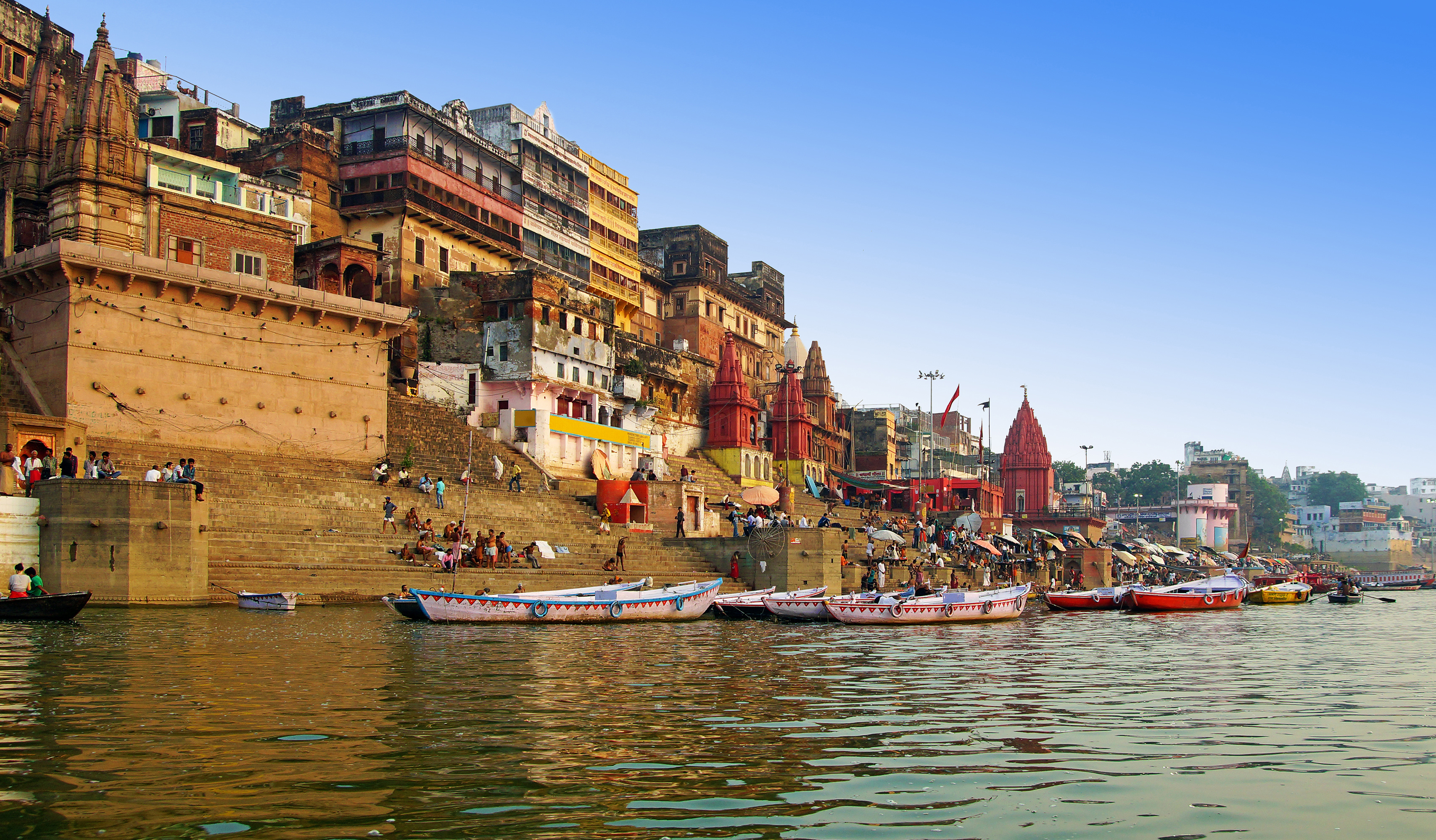 view of the Ganges River with temples and ghats leading down to it in the city of Varanasi