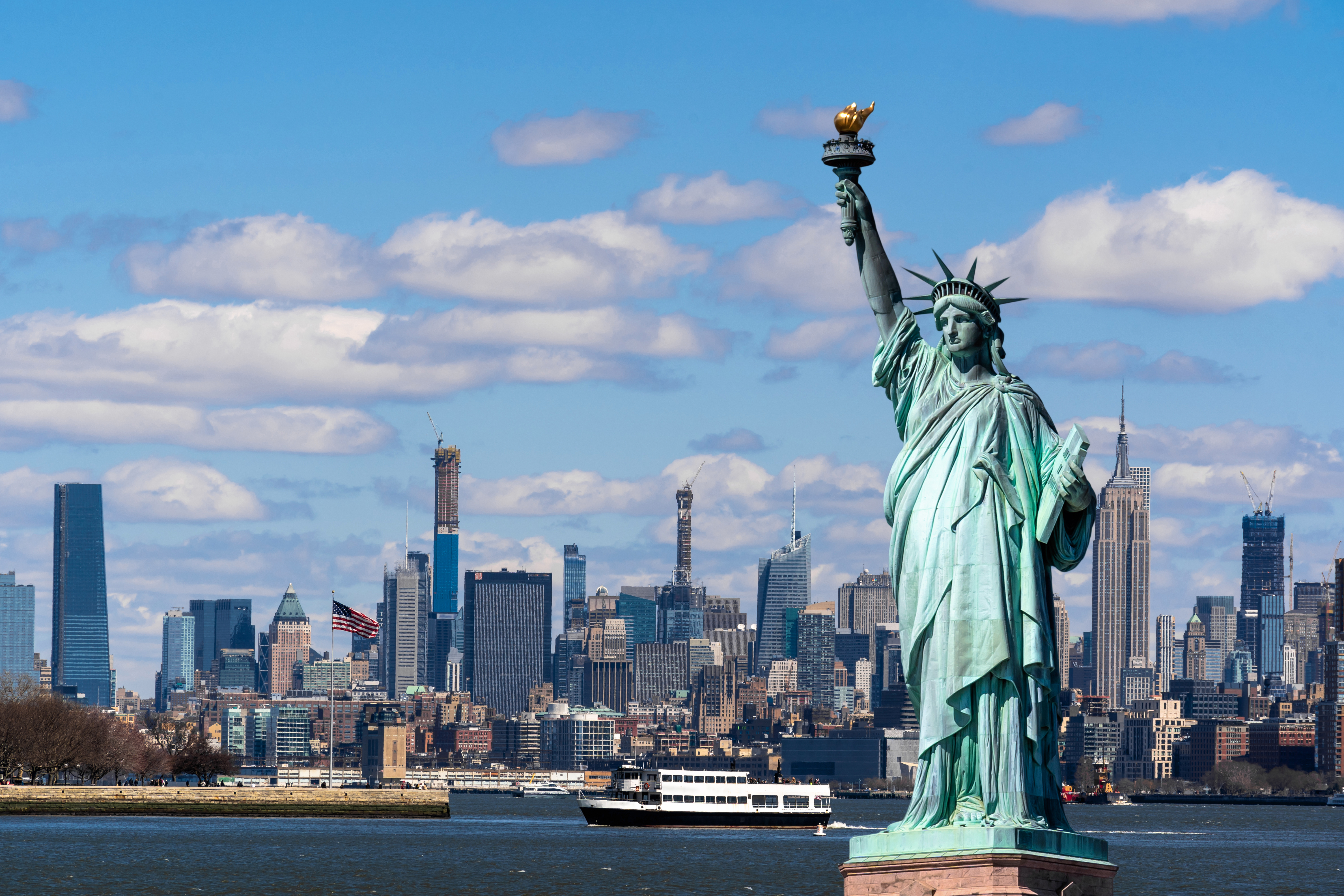 statue of liberty in front of the new york skyline
