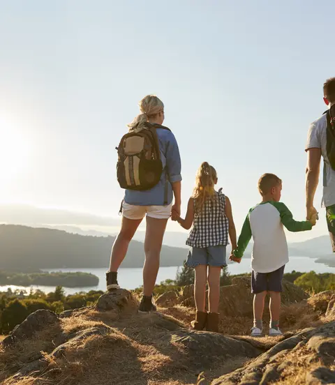 Rear View Of Family Standing At Top Of Hill On Hike Through Countryside In Lake District UK