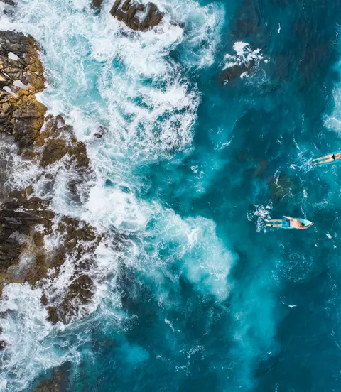 Aerial shot of surfers paddling over blue waters