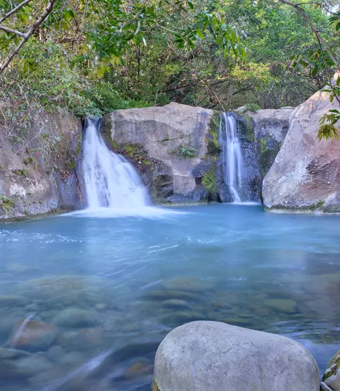 Beautiful blue logoon are surrounded by volcanic rock walls and green foliage