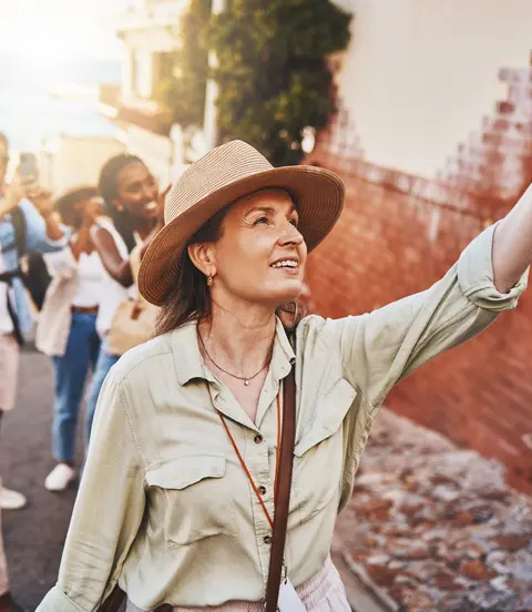 Woman, city guide and group of happy tourists, pointing at local architecture