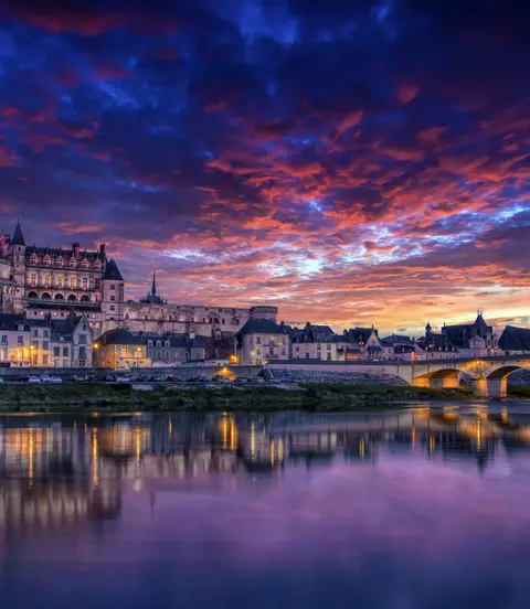 The royal chateau and ancient bridge with a vivid sunset in the background
