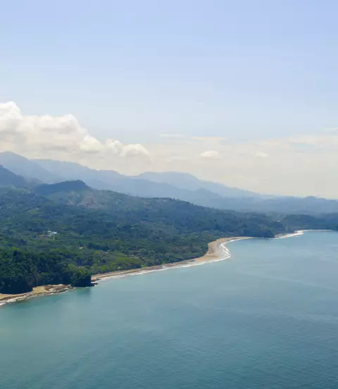 Vibrant tropical forests flow down from the mountains to the sandy beaches along the coast. Aerial view of the Costa Ballena near Dominical, Costa Rica