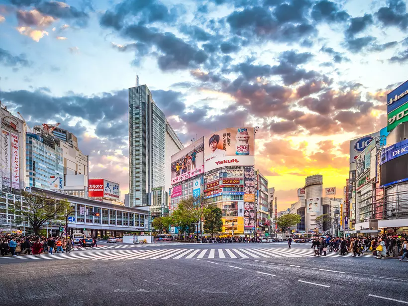 Pedestrians waiting at the traffic light to cross the street at Shibuya Crossing at sunset