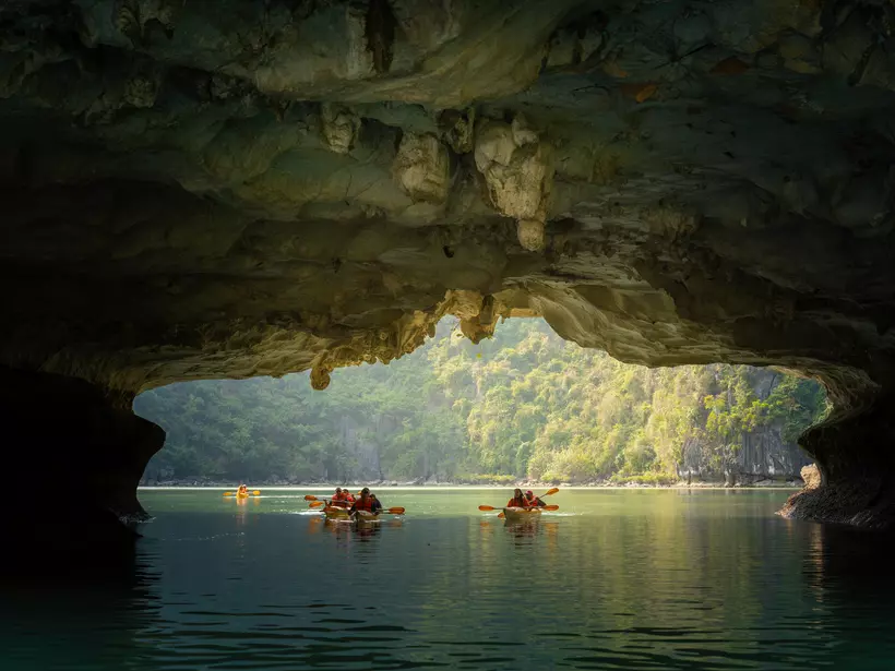 View of tourist exploring calm tropical bay with limestone mountains by kayak.