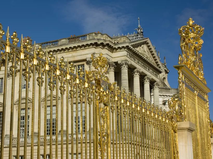 Fragment of golden entrance gates to the Versailles Palace (Chāteau de Versailles) on a sunny summer day