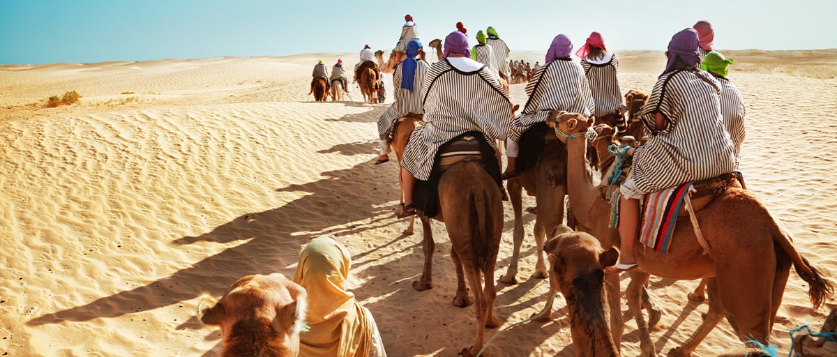 A group of travellers riding a camel in the Sahara Desert in Morocco.