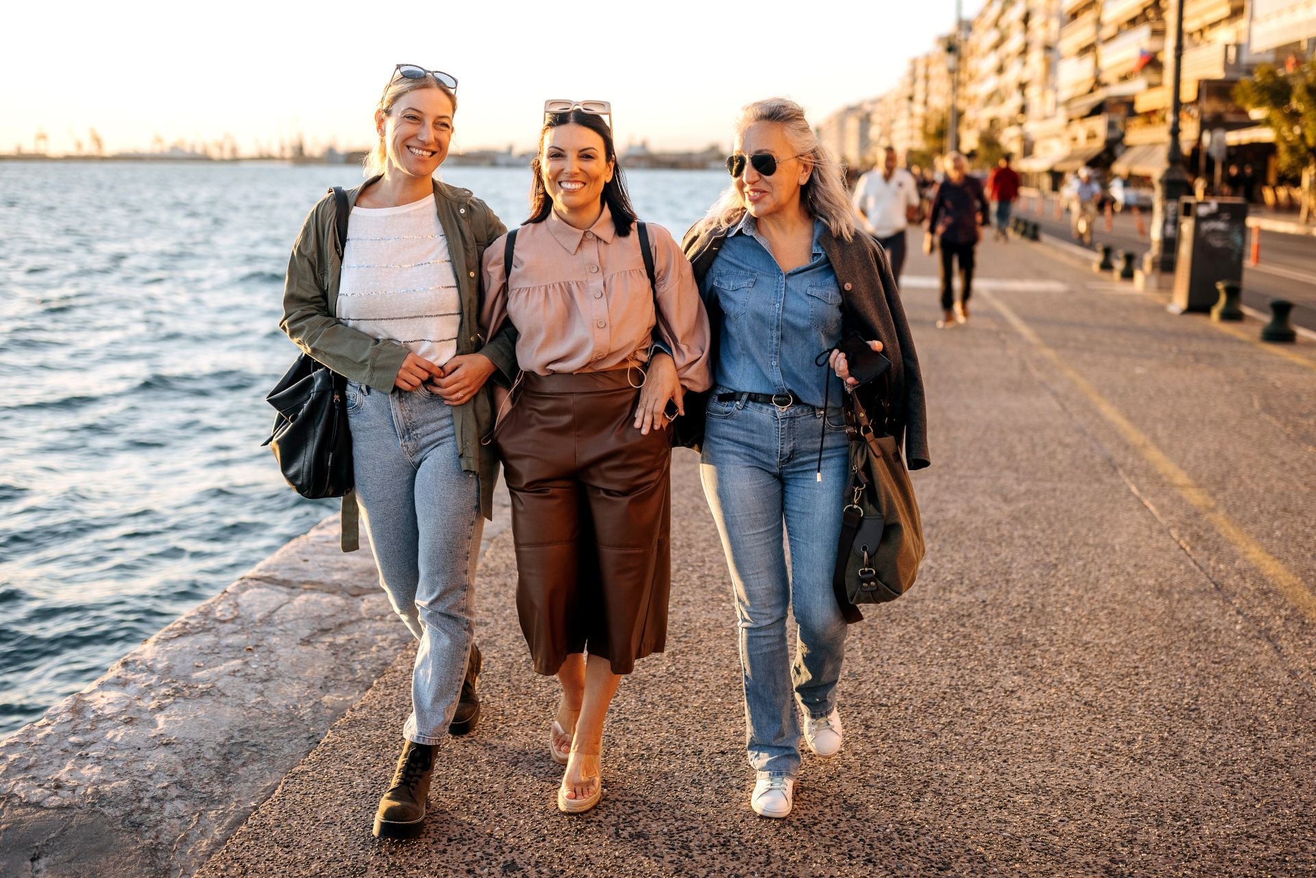 Female friends on holiday walking by the sea in the city