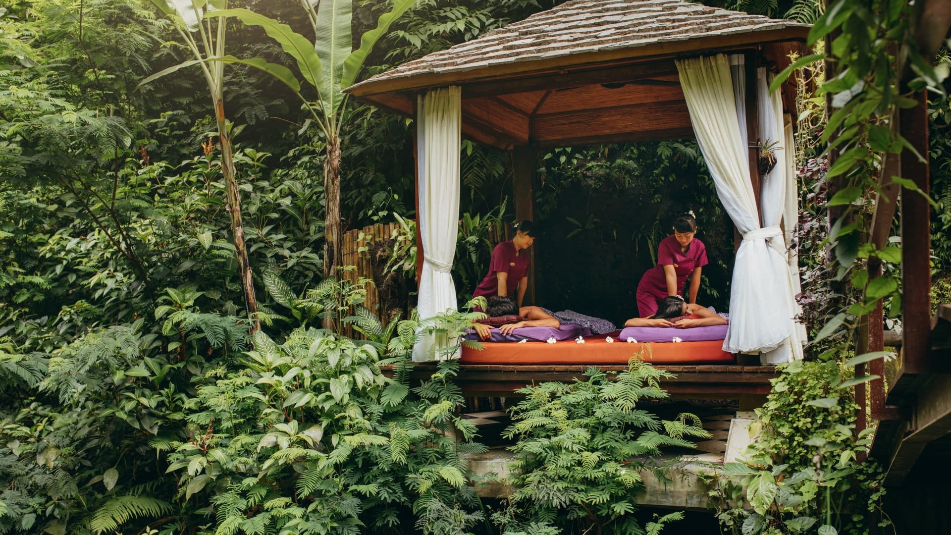 A couple enjoy massages in an outdoor gazebo in the jungle
