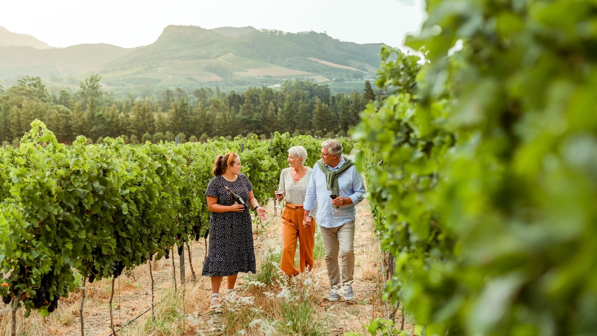Couple getting tour of a vineyard with woman farmer during vacation