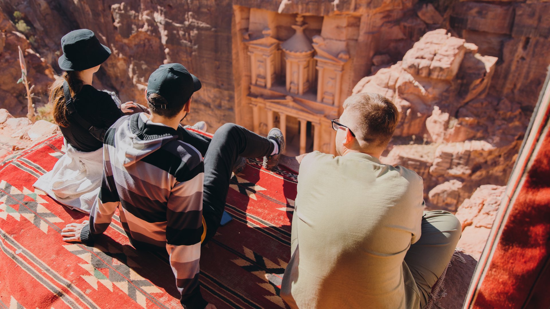 Petra, Jordan Group sitting on the top of the cliff looking at the famous old Petra town gates hidden in the canyon in Jordan, the Middle East