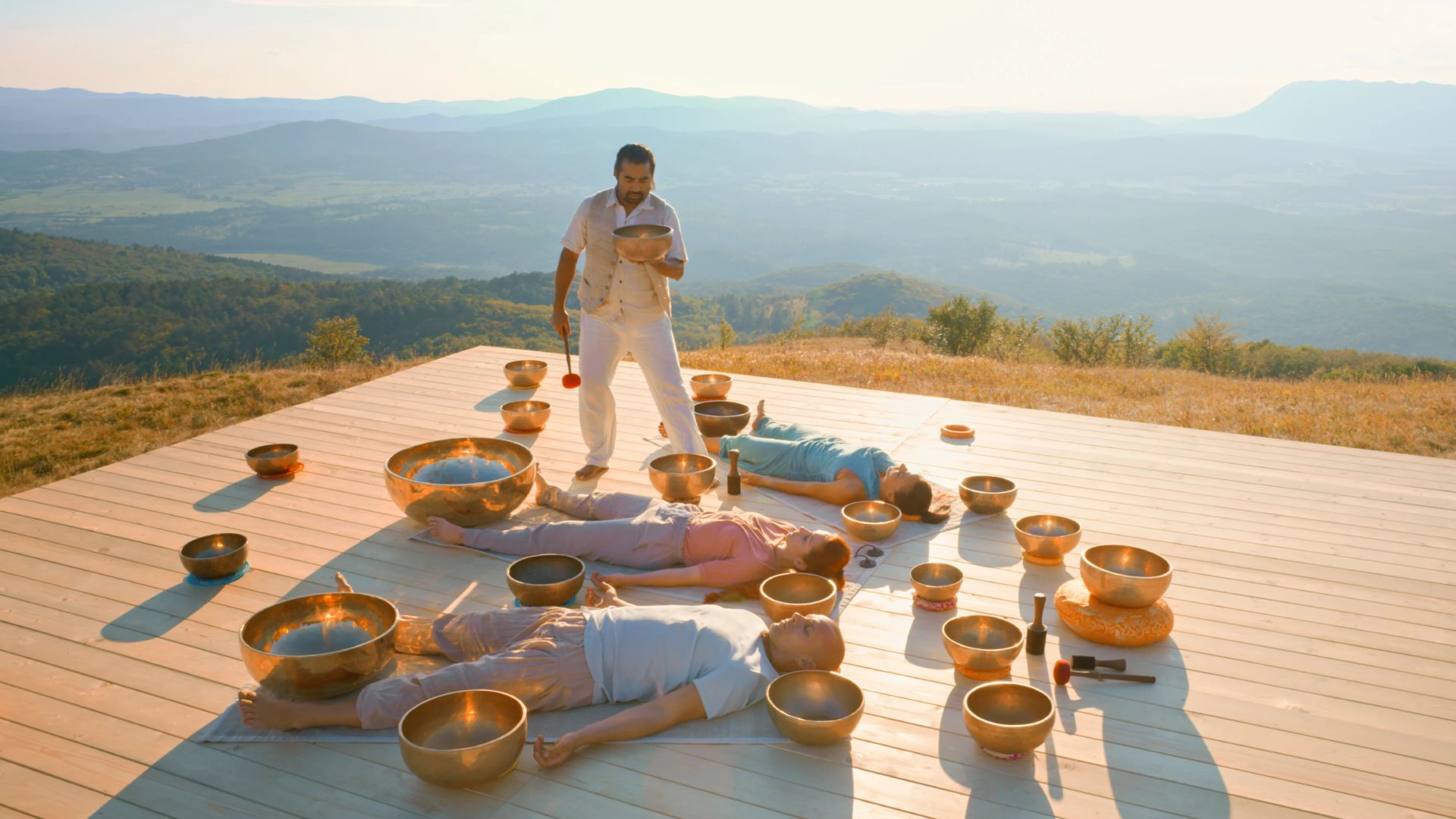 Male therapist playing ring gong while performing music therapy during sunset