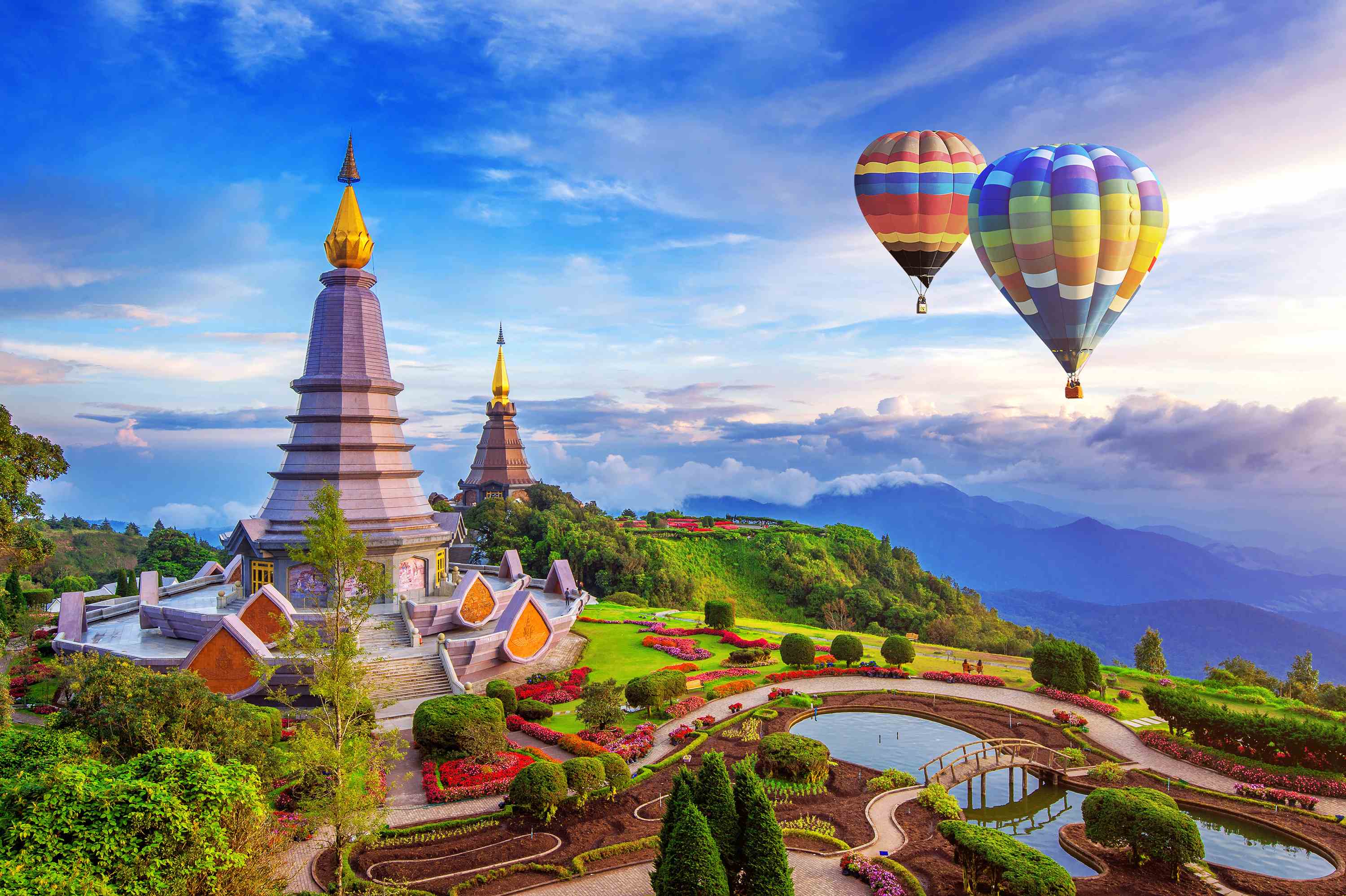 Hot air balloons over mountain landscape with pagodas and rice paddies
