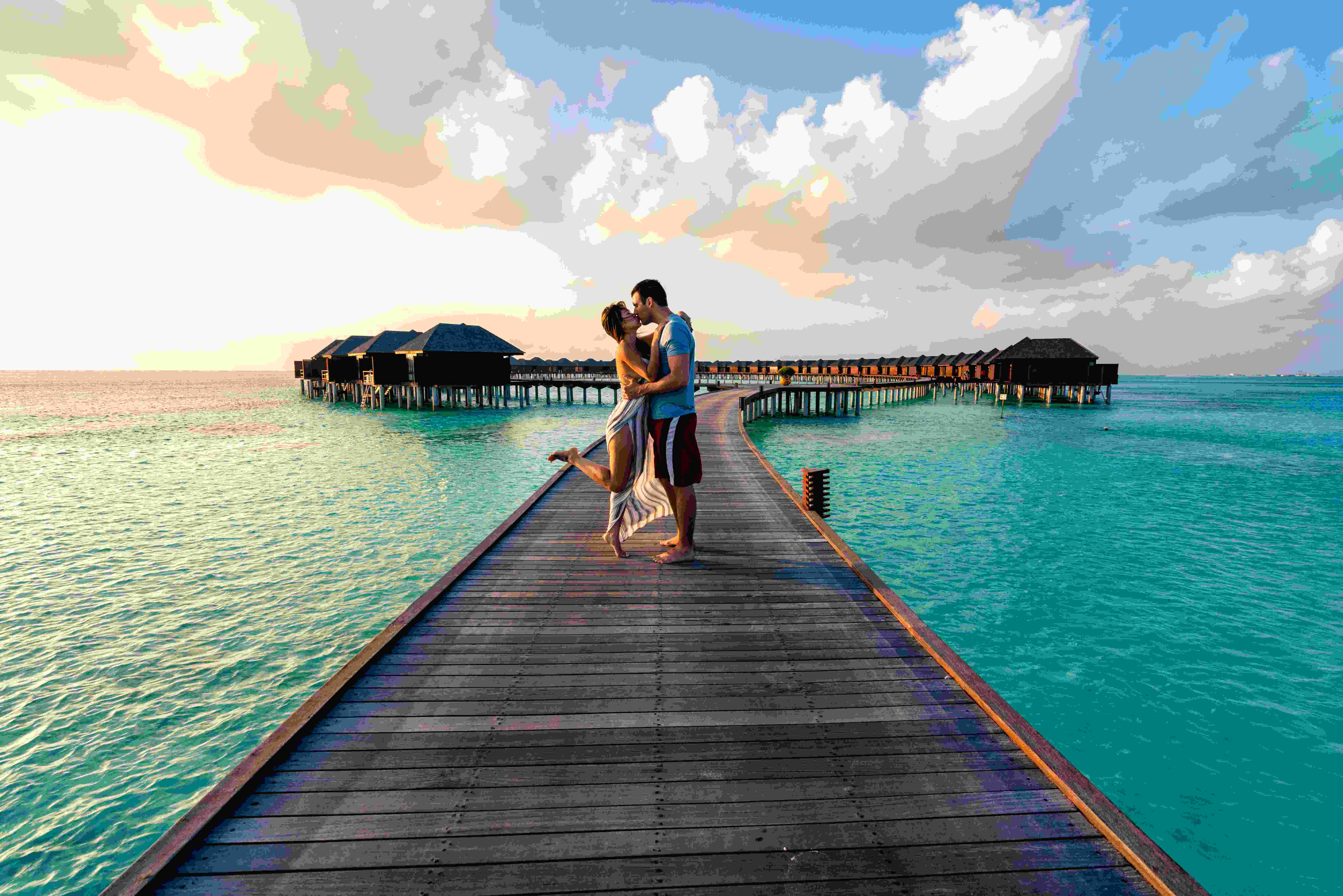 Couple embracing on an overwater boardwalk over the ocean