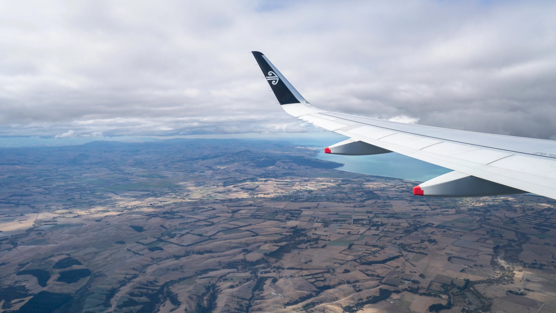 Aerial view of an airplane wing with Air New Zealand logo. Flying above the Canterbury. Image taken on Air NZ flight from Auckland to Christchurch