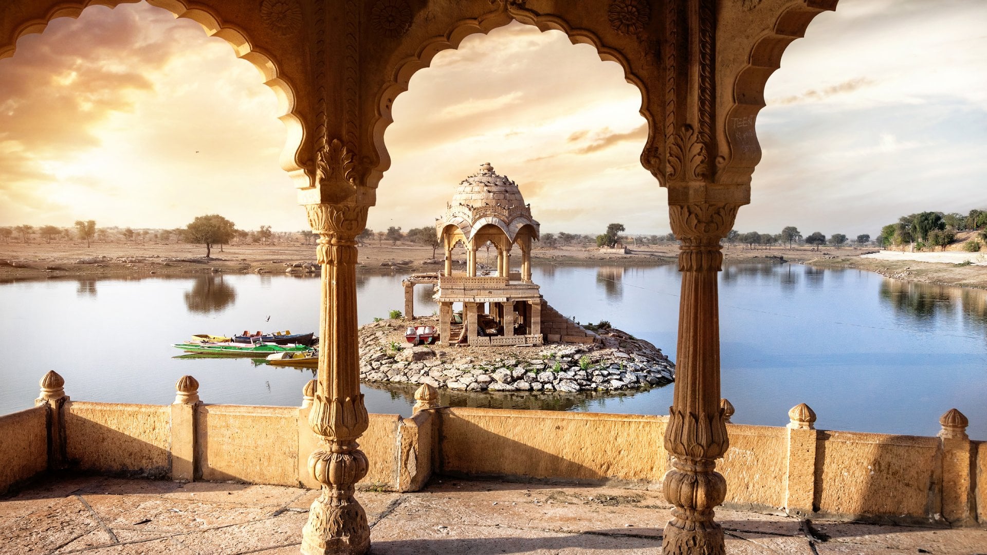 Arches and temple in Gadi Sagar lake at sunset sky in Jaisalmer, Rajasthan, India