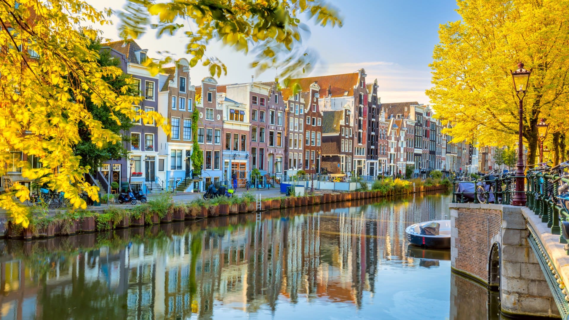 Autumn morning in Amsterdam. Silence. Ancient houses are reflected in the water of the canal, the sun shines through the trees. Lovely morning in Amsterdam