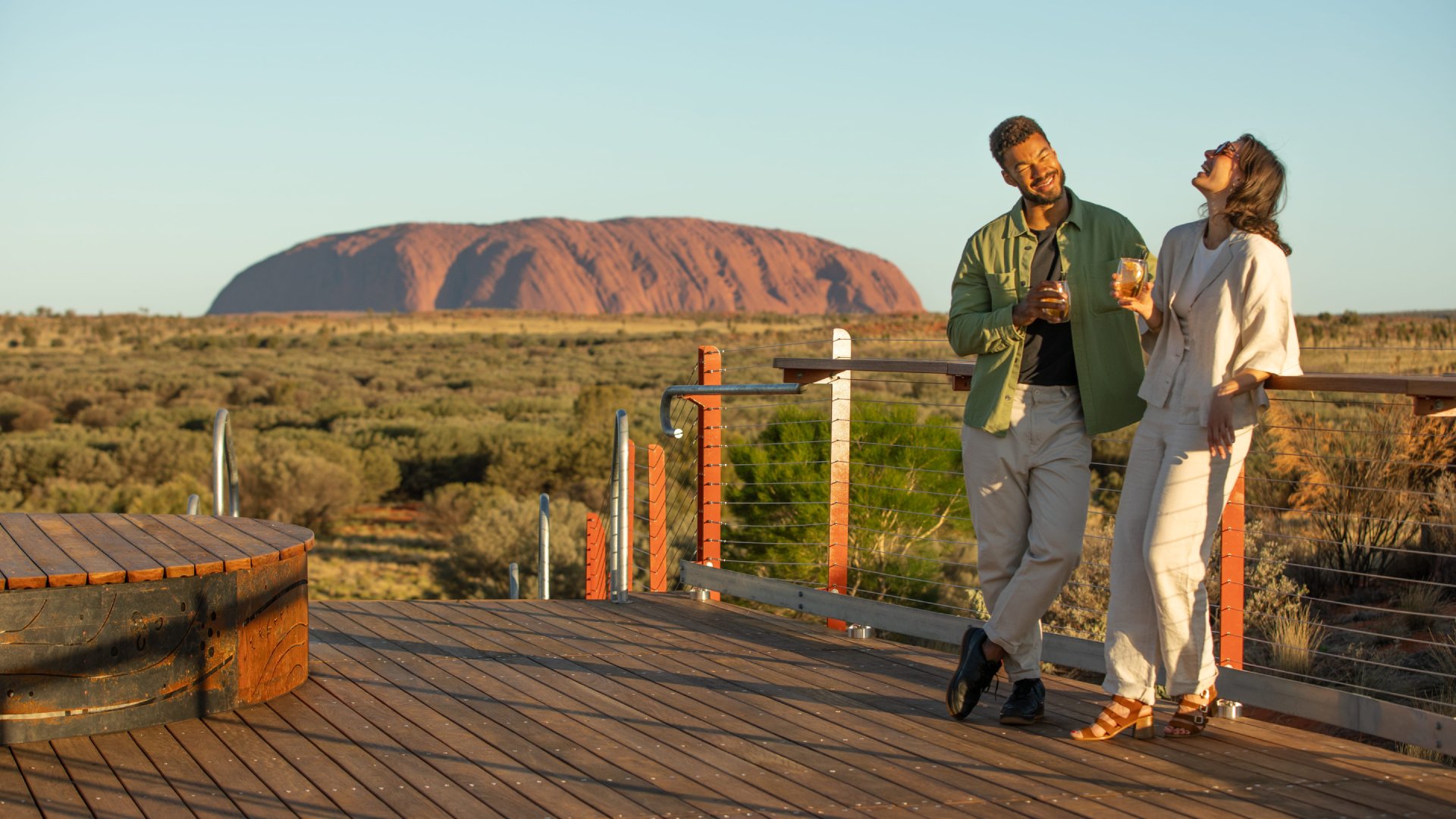 Uluru, Northern Territory(©Tourism Australia) a young couple enjoying drinks on an Australia vacation while Uluru/Ayers Rock is in the background