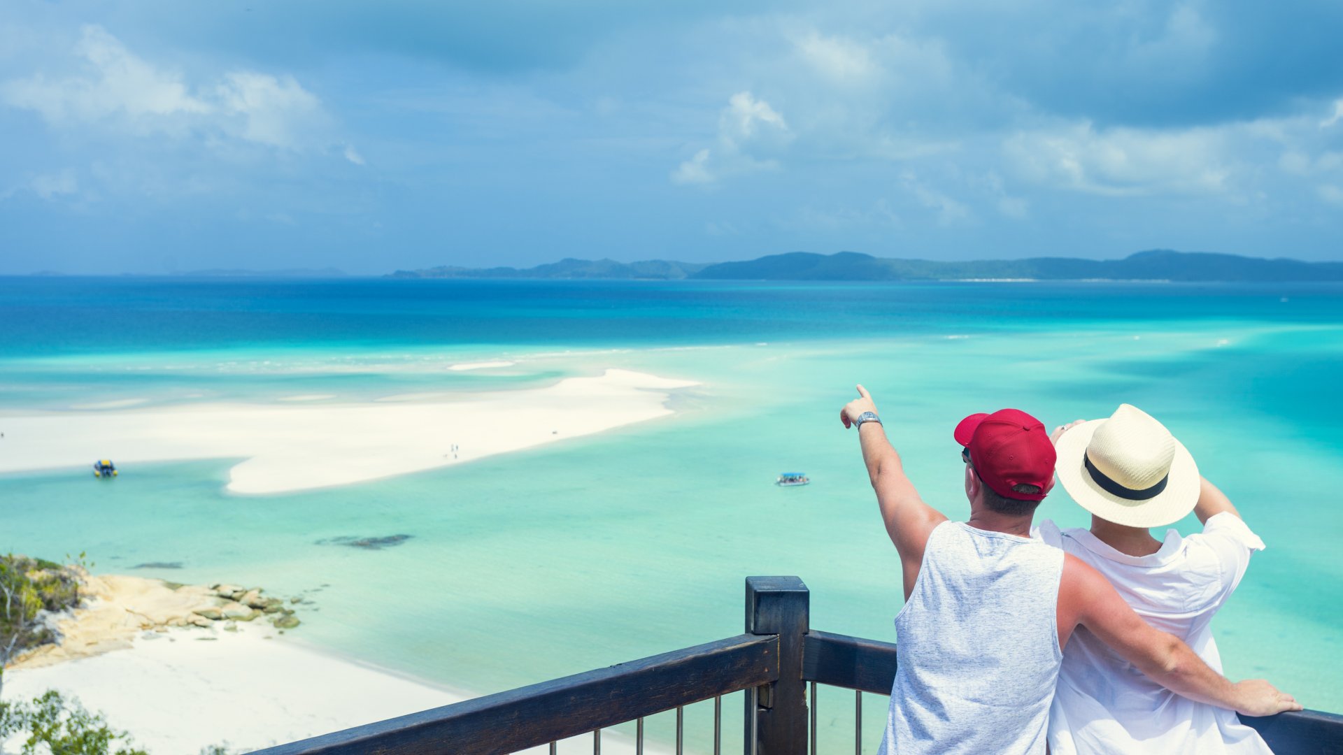 Couple looking at the view of Whitehaven beach. Whitehaven beach is in the Whitsunday islands in Queensland, Australia.