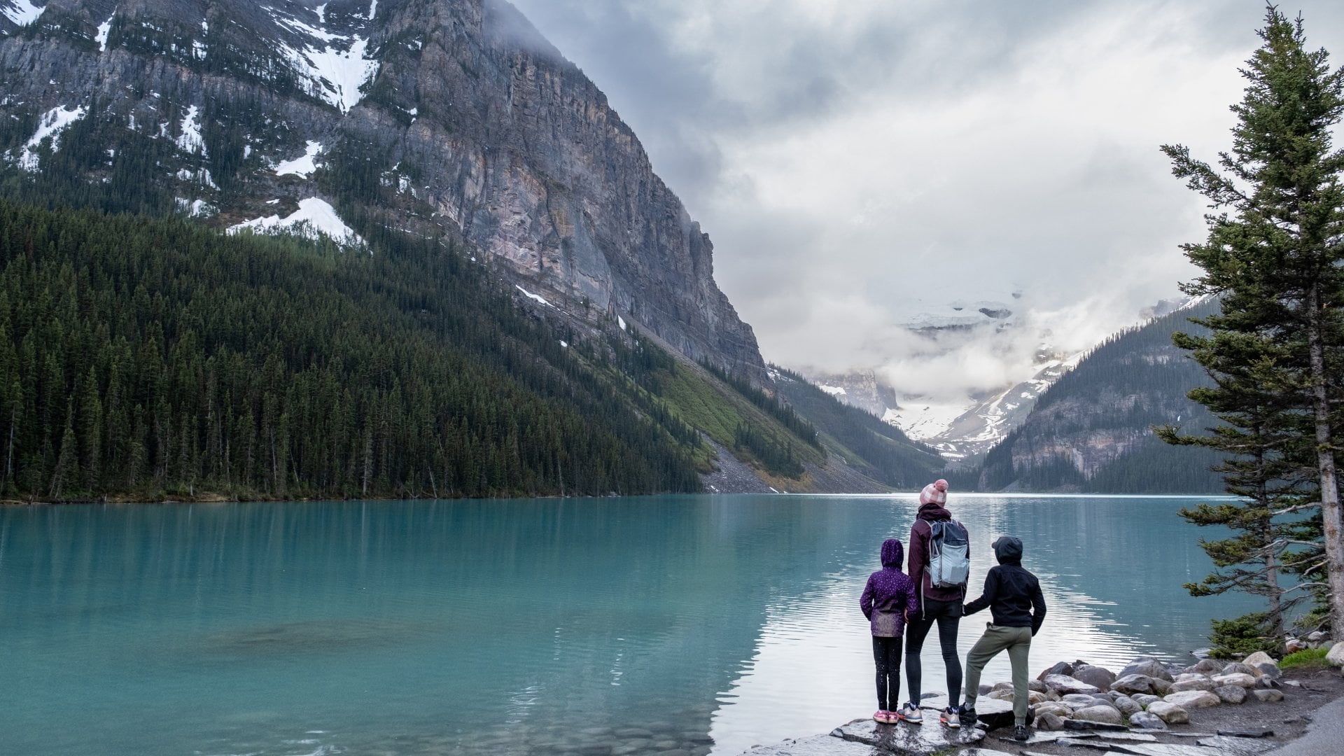 Family hiking around a pristine glacial lake in Banff National Park, Canada.