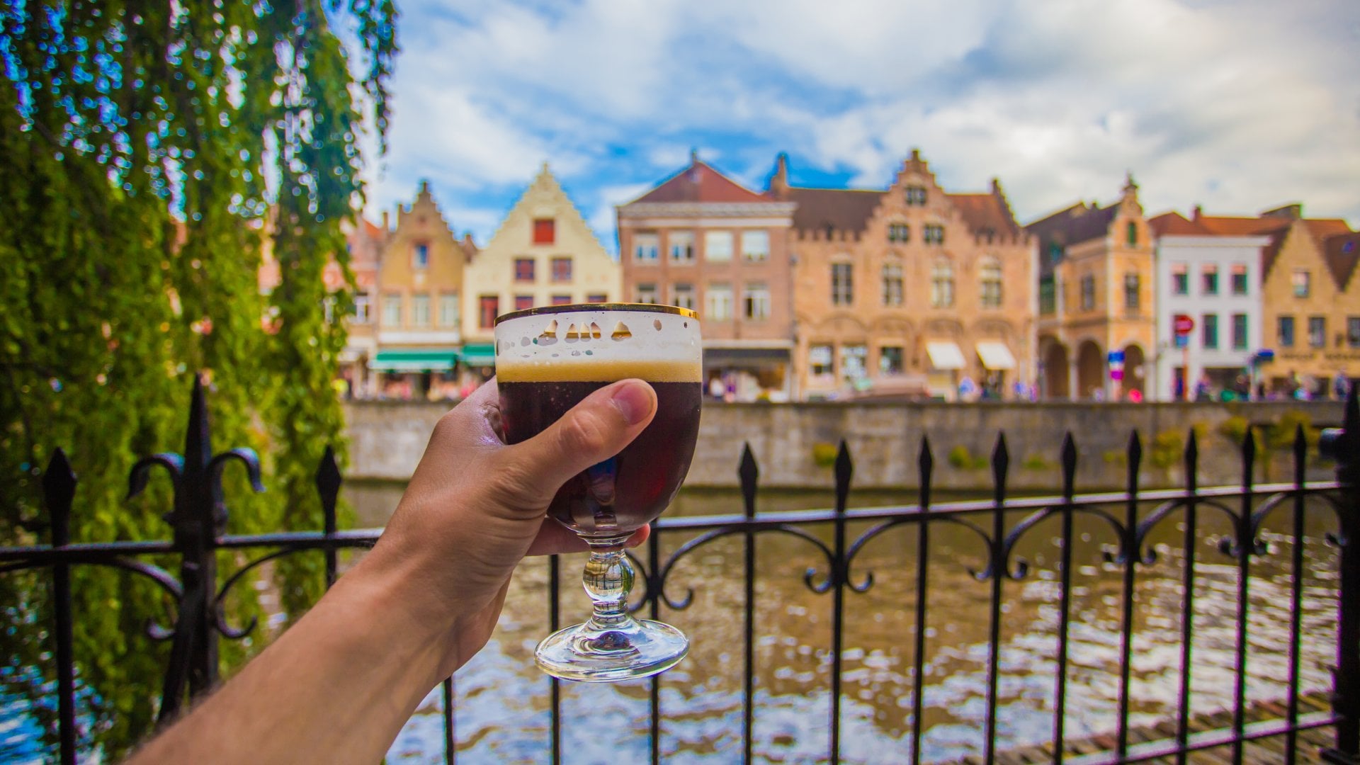 Full glass of beer with Bruges cityscape background, Belgium Vacations