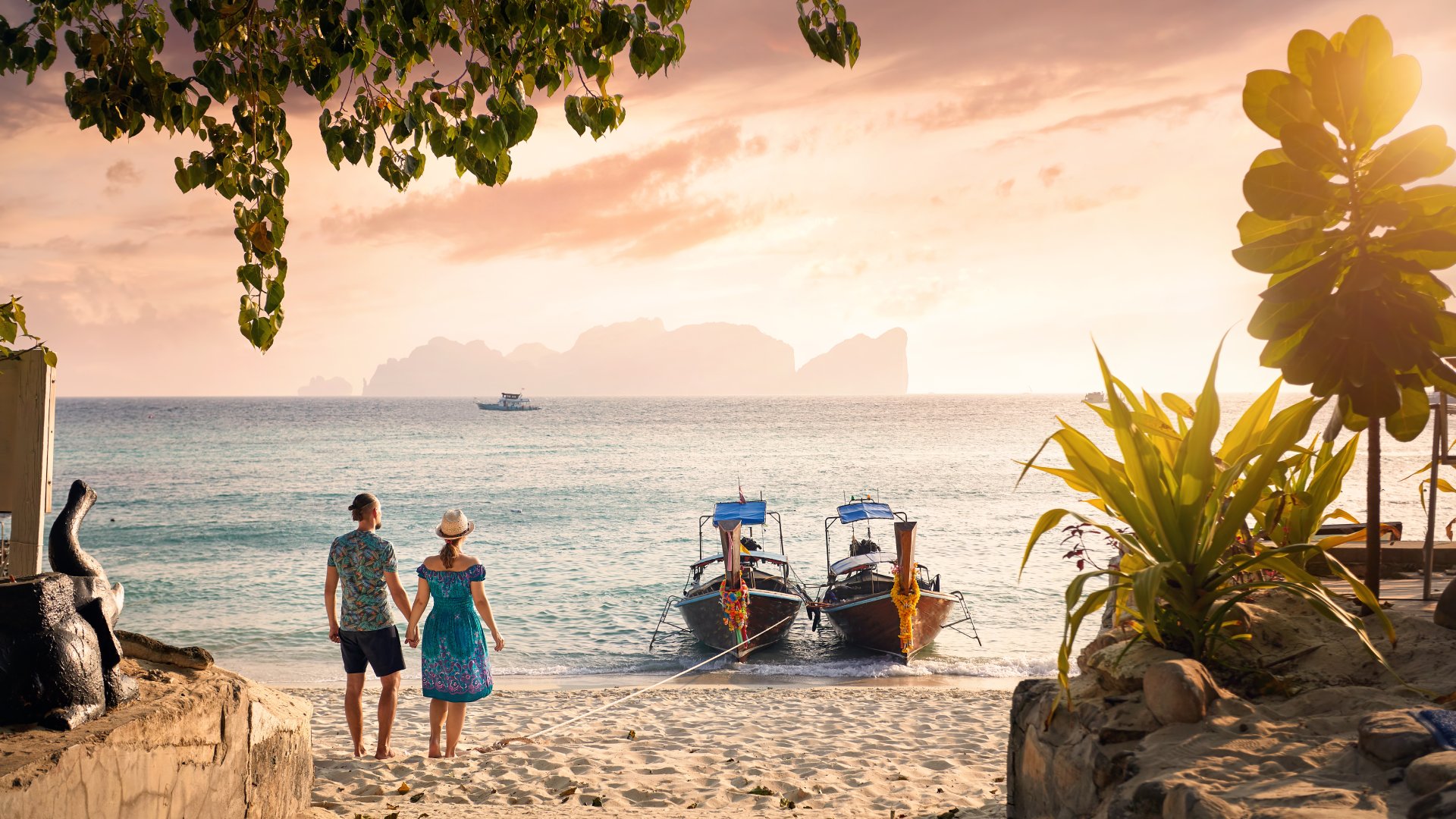 Happy couple on the tropical beach of Phi Phi island at sunset in Southern Thailand.